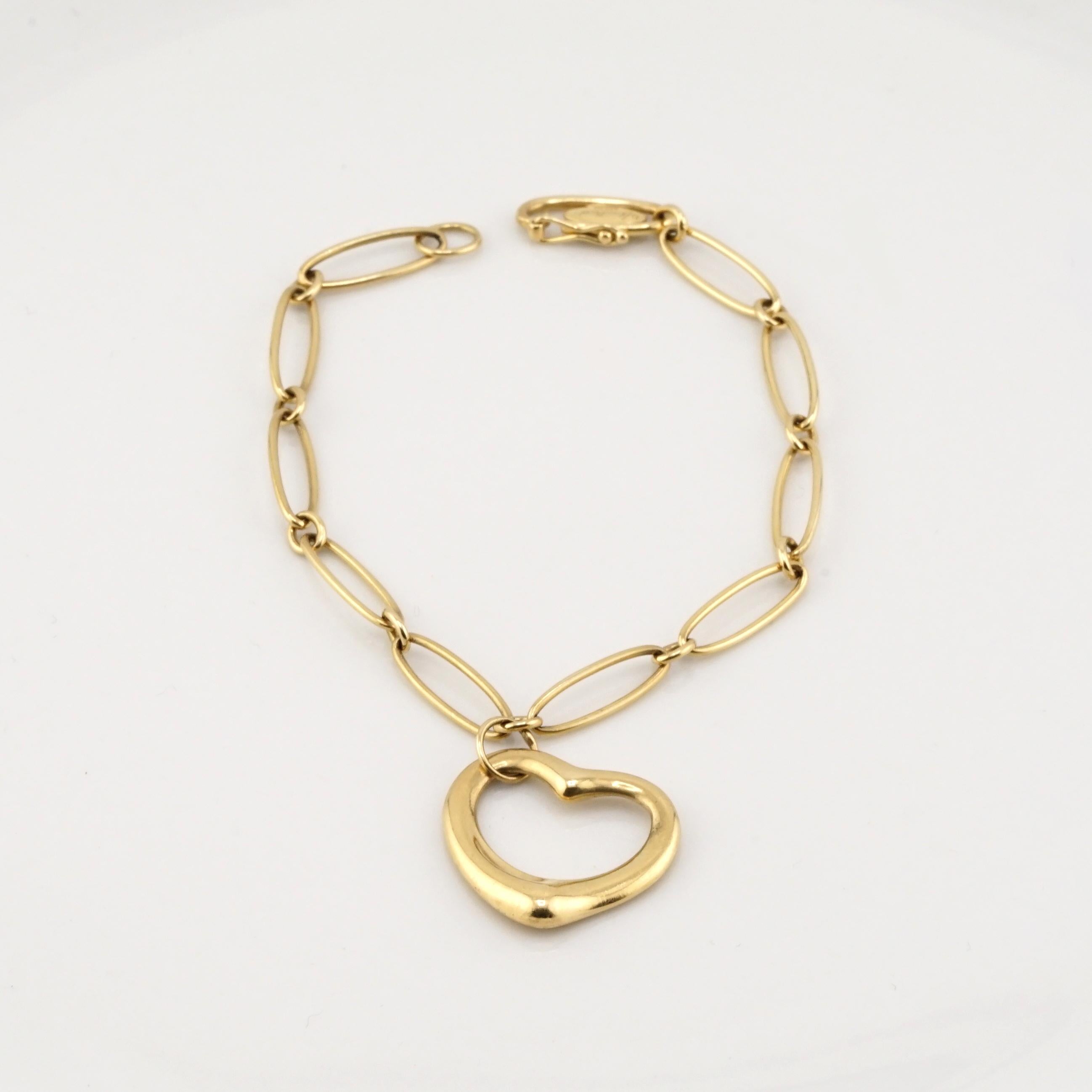 This elegant Tiffany & Co. bracelet is a timeless piece of fine jewelry, crafted from luxurious 18K yellow gold. Featuring a classic chain-link design, the bracelet is adorned with a signature open-heart charm, symbolizing love and