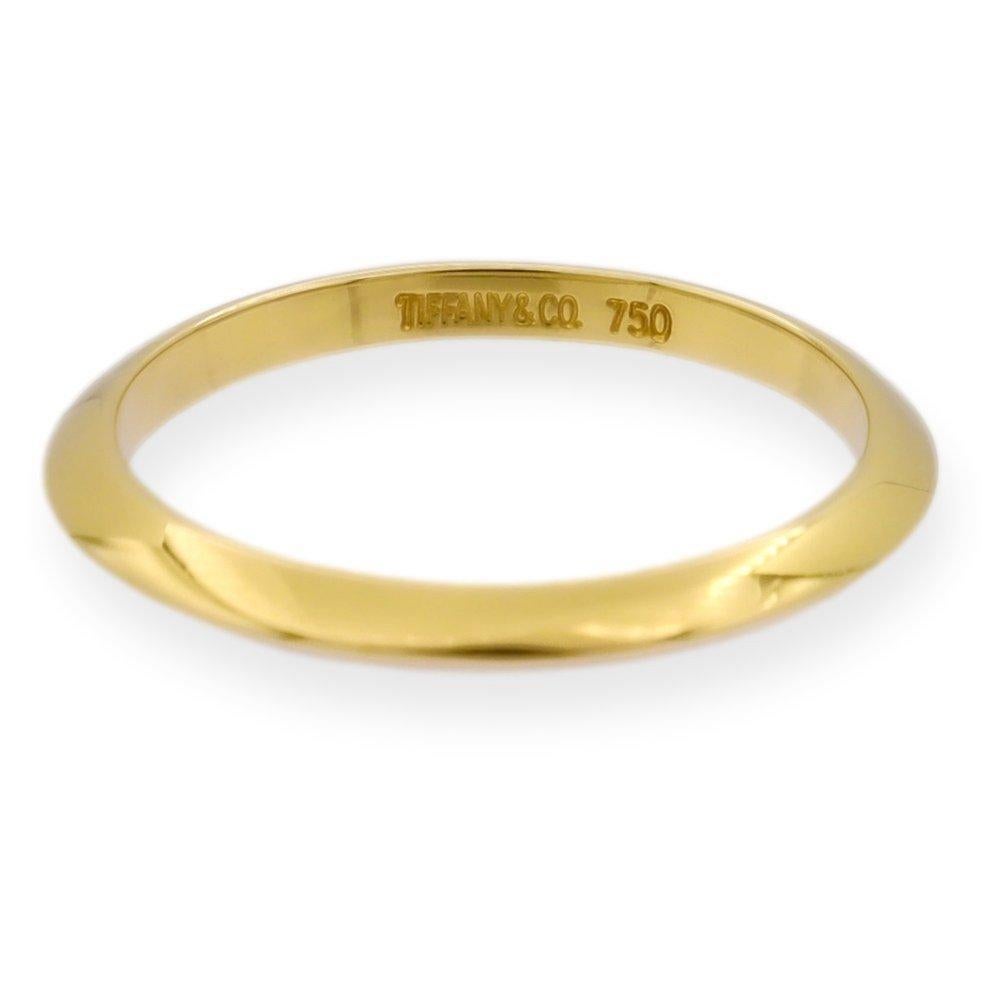 Tiffany & Co. 2mm Knife-Edge wedding band ring finely crafted in 18K yellow gold. Complements any yellow gold Tiffany solitaire engagement ring. Fully hallmarked with logo and metal content. 

Ring Specifications

Brand: Tiffany & Co. 
Style: