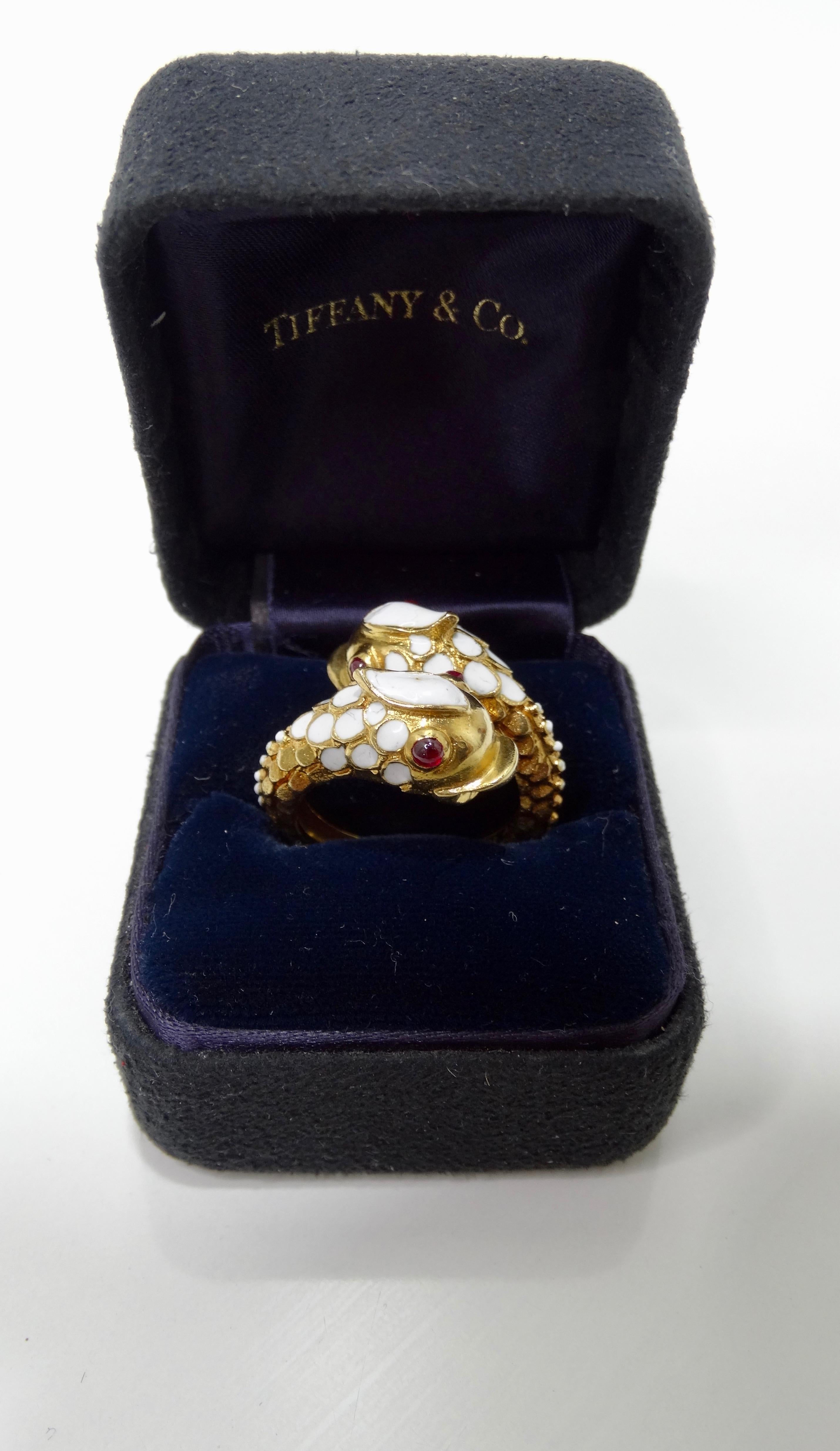 Add this rare Tiffany & Co. treasure to your collection! Circa mid-20th century, this Tiffany & Co. ring has an 18k freeform band crafted into the shape of two koi fish with white enamel filled scales and cabochon cut Ruby eyes. Interior of band is