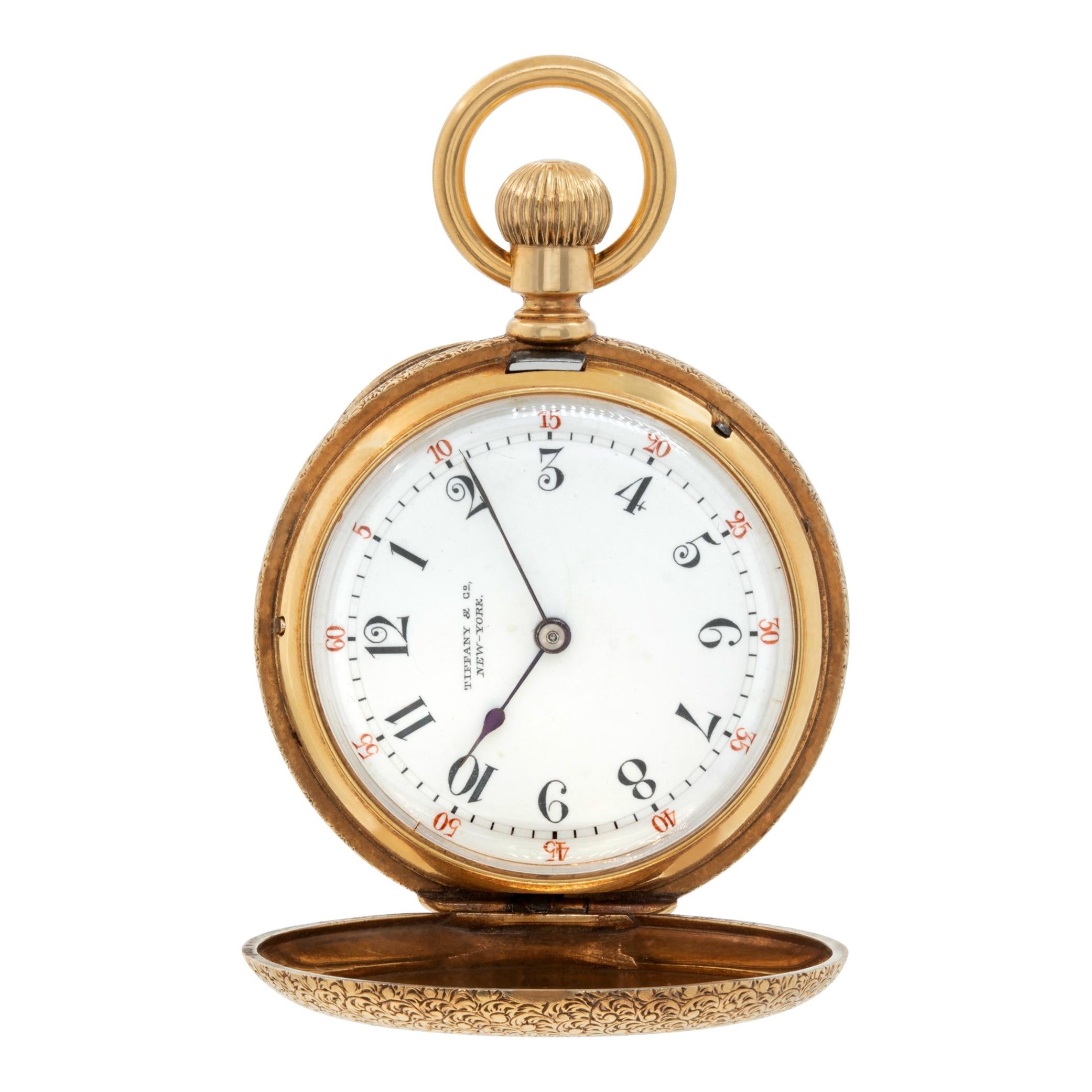 Tiffany & Co. decoratively engraved hunter case pocket watch in 18k yellow gold. 35mm case size. Engraved with 