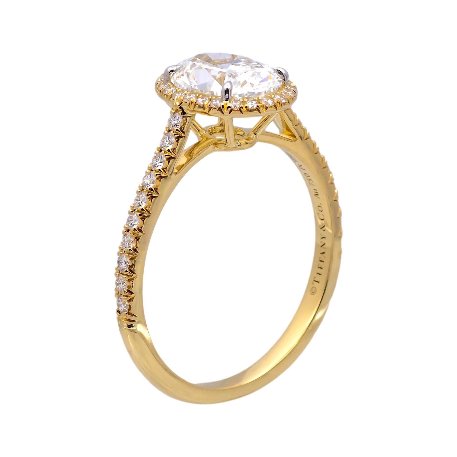 Tiffany & Co. Soleste Diamond Engagement ring featuring a 1.72 ct Oval Shape diamond center graded bright F color and fine VS1 clarity. The center diamond is finely crafted in 18K Yellow Gold with platinum prongs accented by a bead set diamond halo