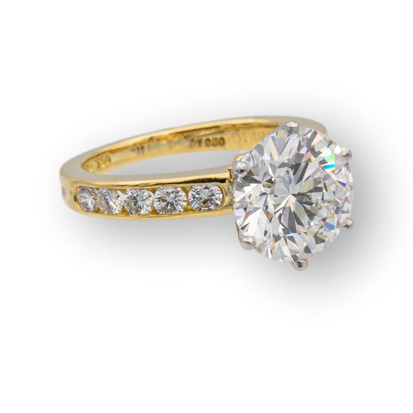 Vintage Tiffany & Co. Diamant Verlobungsring mit Kanal gesetzt Diamantband  Fein in 18 Karat Gelbgold gefertigt, mit einem 2,69 ct. Zentrum F Farbe, VVS1 Klarheit in Platin Zacken gesetzt. Der zentrale Diamant wird von 5 kanalgefassten runden