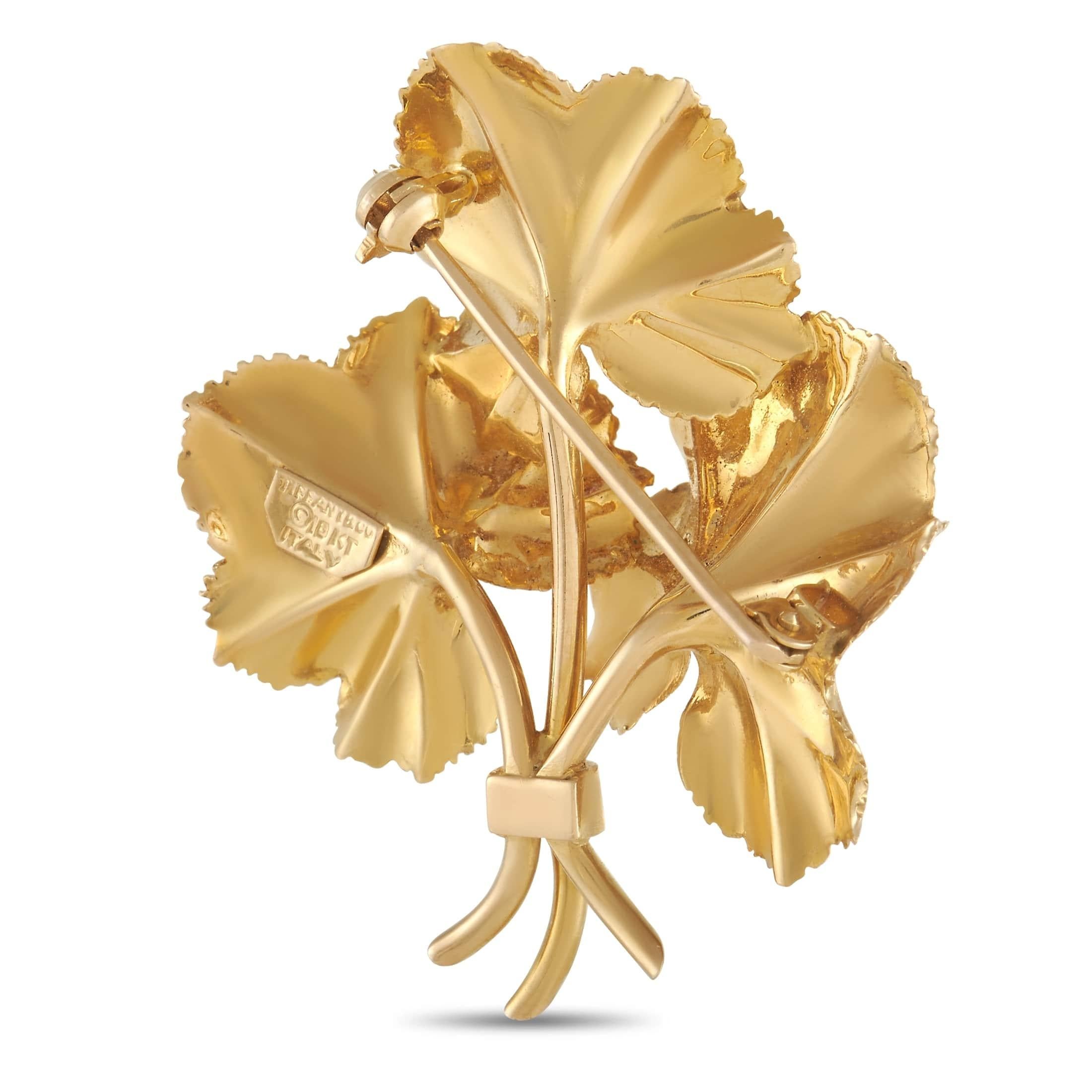This lovely flower brooch from Tiffany & Co. features a trio of beautiful flowers crafted and detailed in 18K yellow gold. The center of each flower is marked with a cluster of small round rubies. The brooch measures 1.88 inches by 1.5 inches and