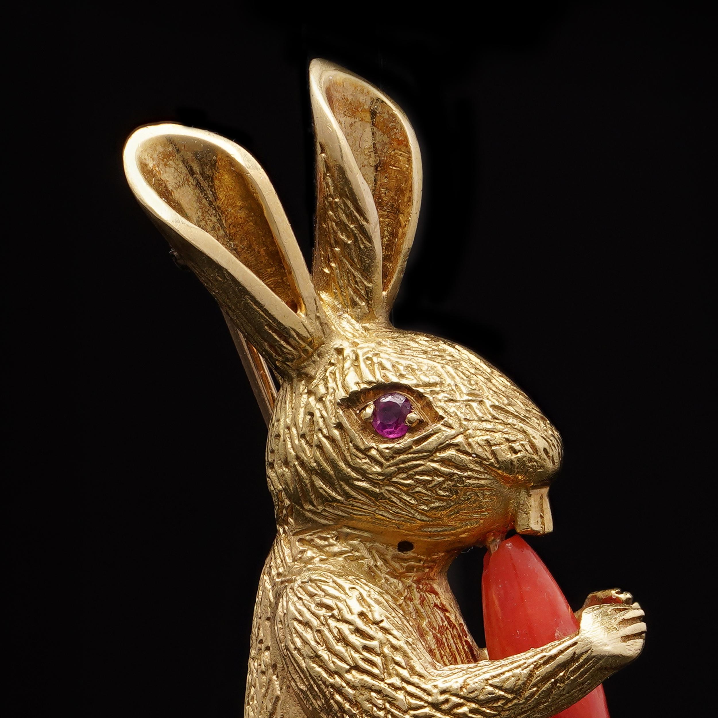 Eine verspielte Brosche mit hohem Sammlerwert von Tiffany & Co. aus luxuriösem 18-karätigem Gelbgold. Dieses entzückende Stück ist als stehender Hase modelliert, der eine geschnitzte Karotte aus Koralle in den Pfoten hält und dessen Fell fein