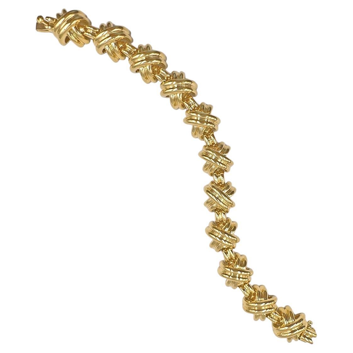 Classic Tiffany link bracelet in polished 18kt yellow gold.  Eleven raised, curved 'X' motif links with adjoining ribbed gold bar links.  Hidden safety clasp with fold under latch.  Signed 