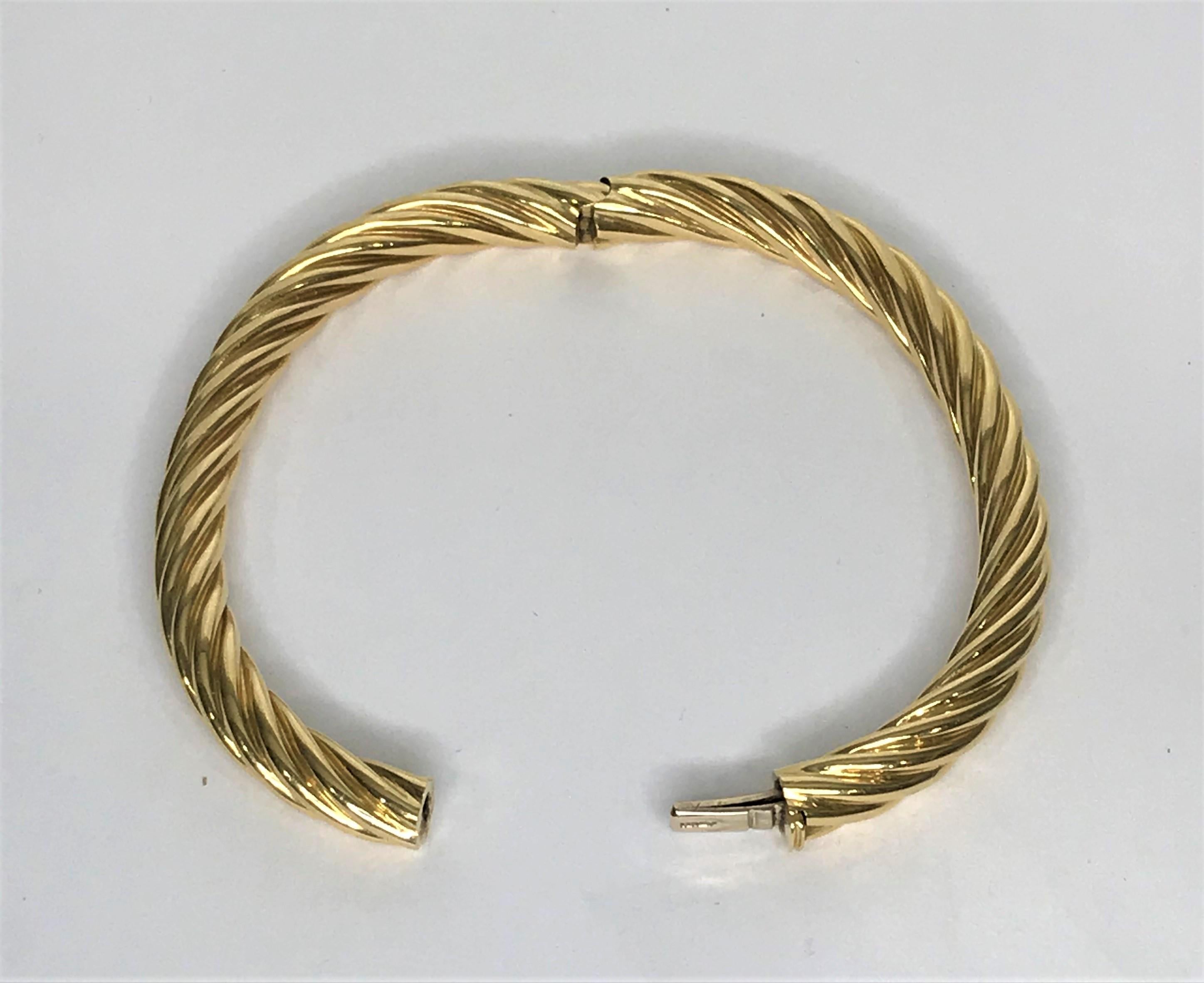 Tiffany & Co. 18 karat gold twist bangle bracelet.
18 karat solid yellow gold  hinged bangle bracelet.  
Oval shape to fit wrist.  Twisted design, polished gold, approximately 6.7mm wide.
Approximately 7 inch inside circumference.
Hidden box clasp-