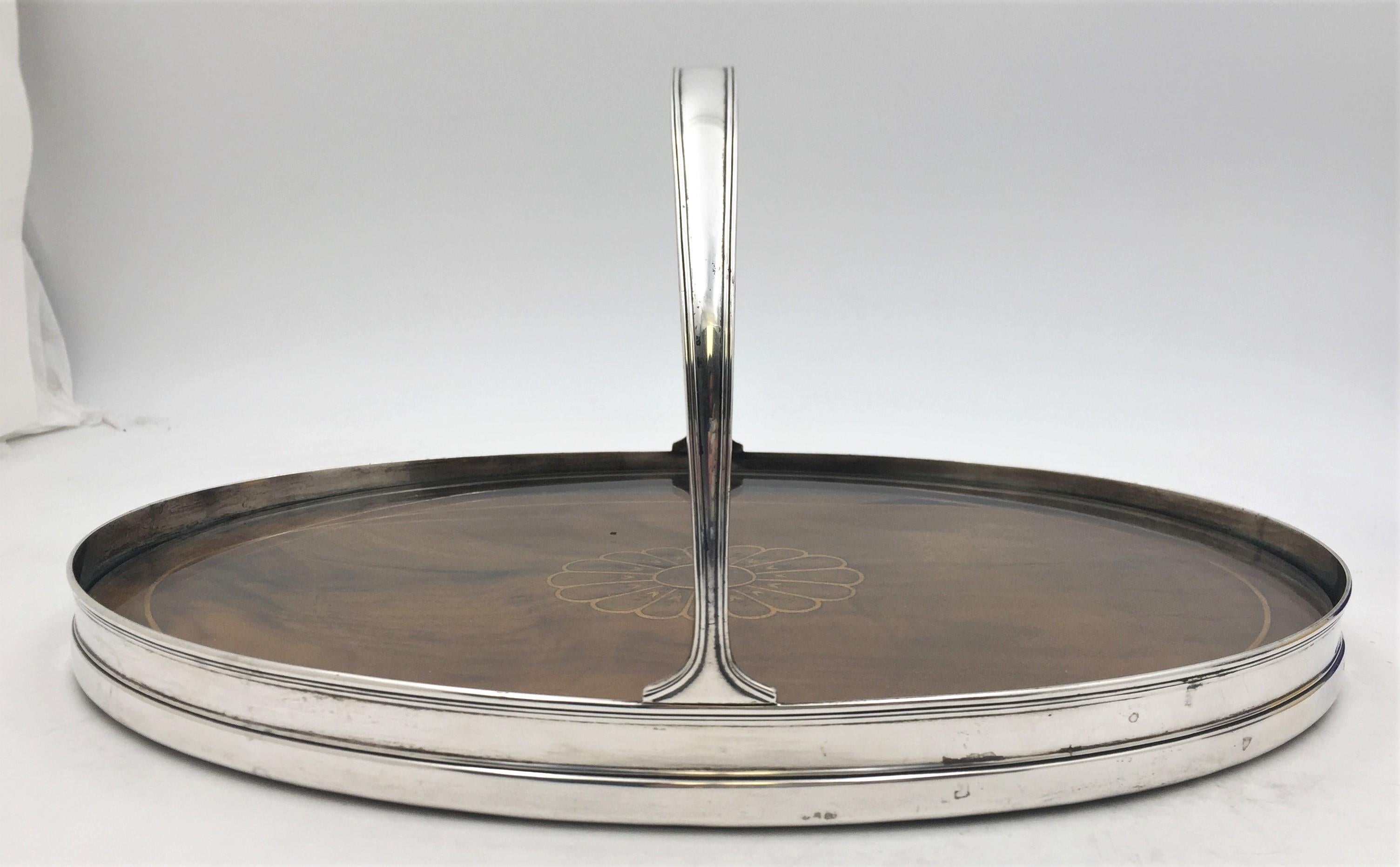 Tiffany & Co. sterling silver and two-tone wood bar tray in pattern 18852 from 1915 and in Art Deco style with a beautiful flower motif at the center and with a geometrically inspired design. It measures 13 7/8'' in length by 9 1/8'' in width by 6
