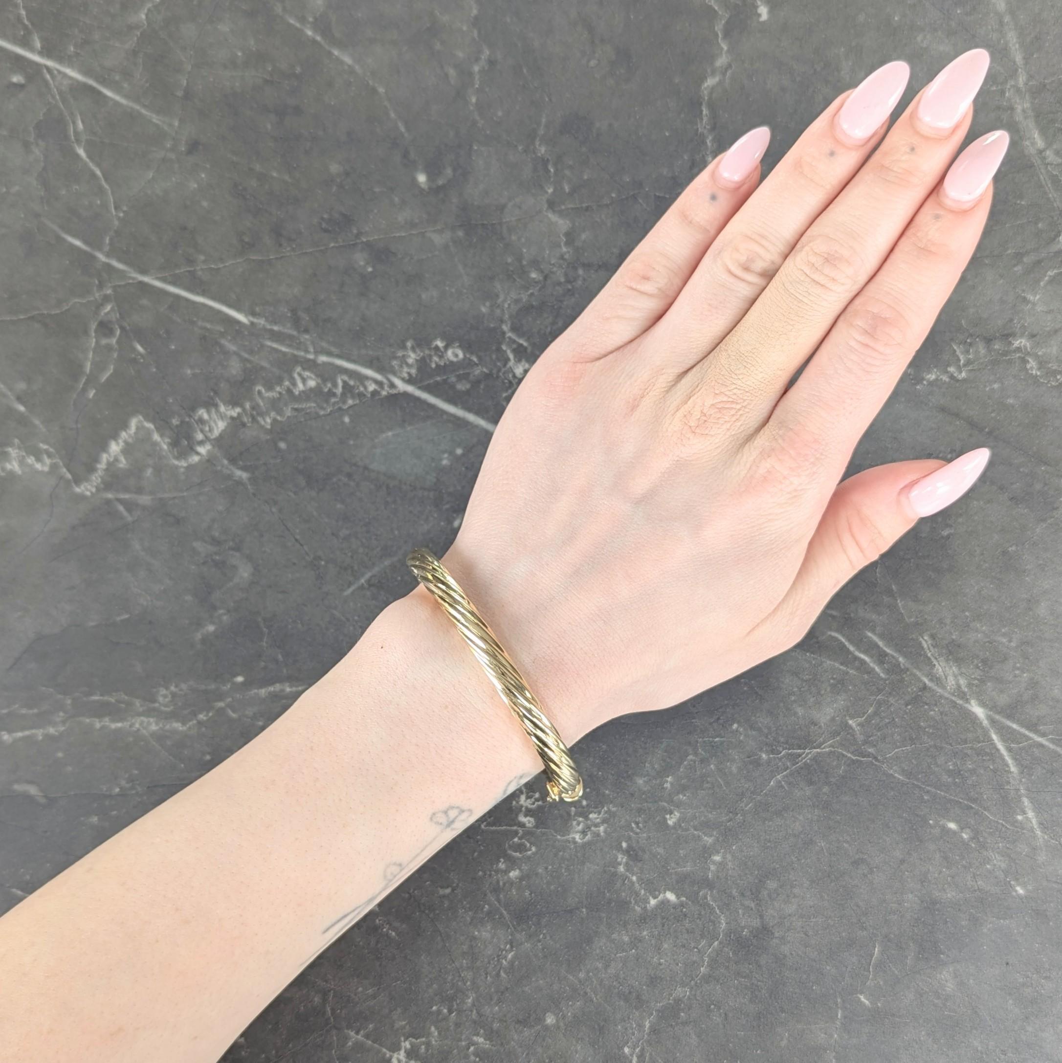 Designed as an oval shaped bangle with fluted detail
Depicting a twisted rope motif throughout
With a high polish finish
Opens on a hinge via press release clasp
With figure eight safety
Stamped for 18 karat gold, Italy
With maker's mark for Tiffany