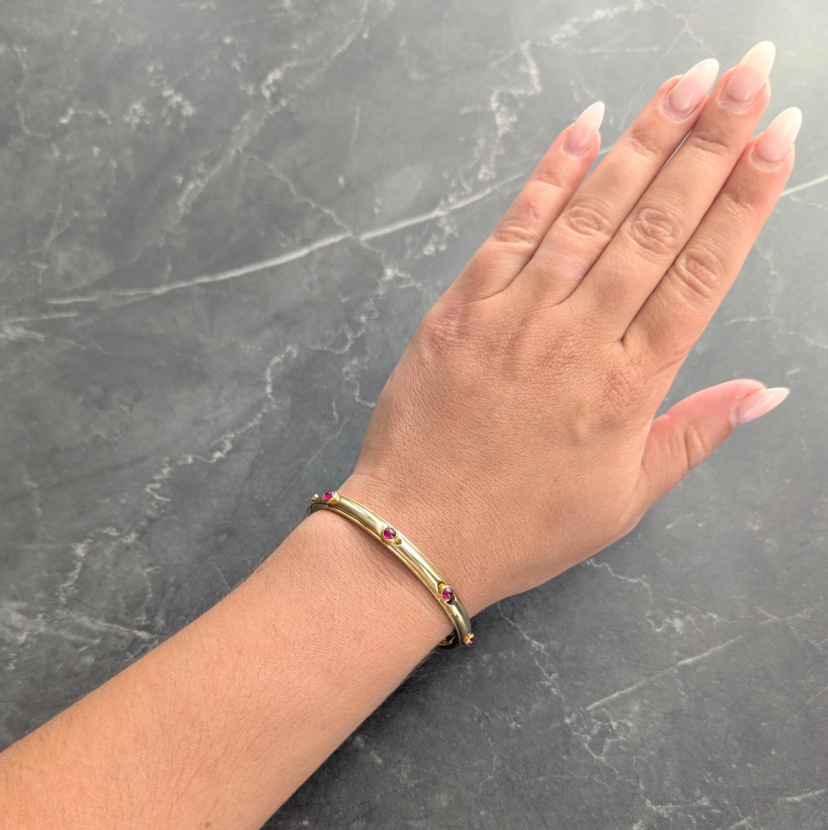 Designed as an oval shaped bangle bezel set with round ruby cabochons
Weighing approximately 2.00 carats total - medium purplish red
Opens on a hinge via press release clasp
With hinged figure eight safety
Stamped for 18 karat gold
Fully signed for