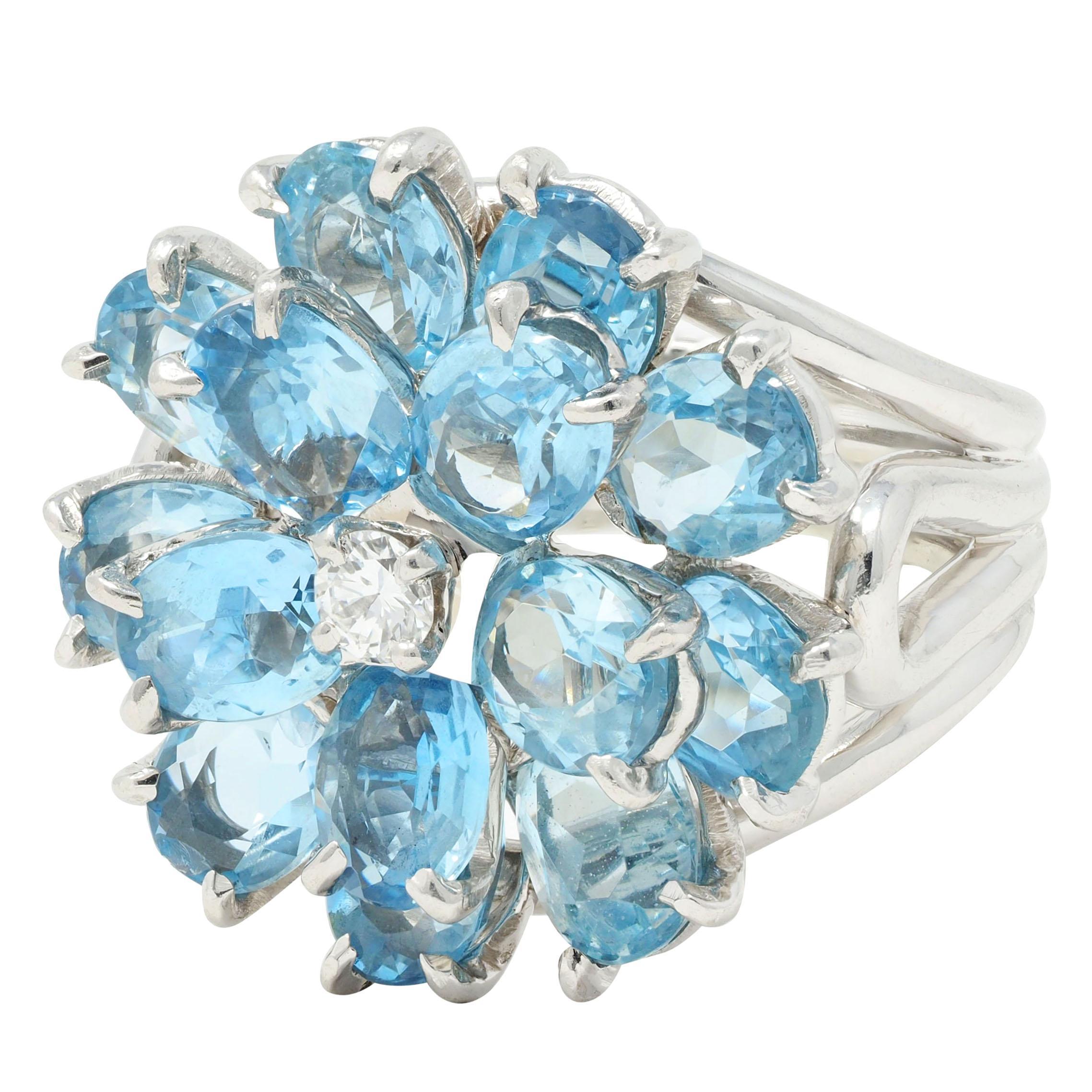 Designed as a flower motif comprised of oval cut aquamarine petals 
Weighing approximately 5.61 carats total - transparent light blue 
Prong set in a wire basket - centering a round brilliant cut diamond 
Weighing approximately 0.10 carat - eye
