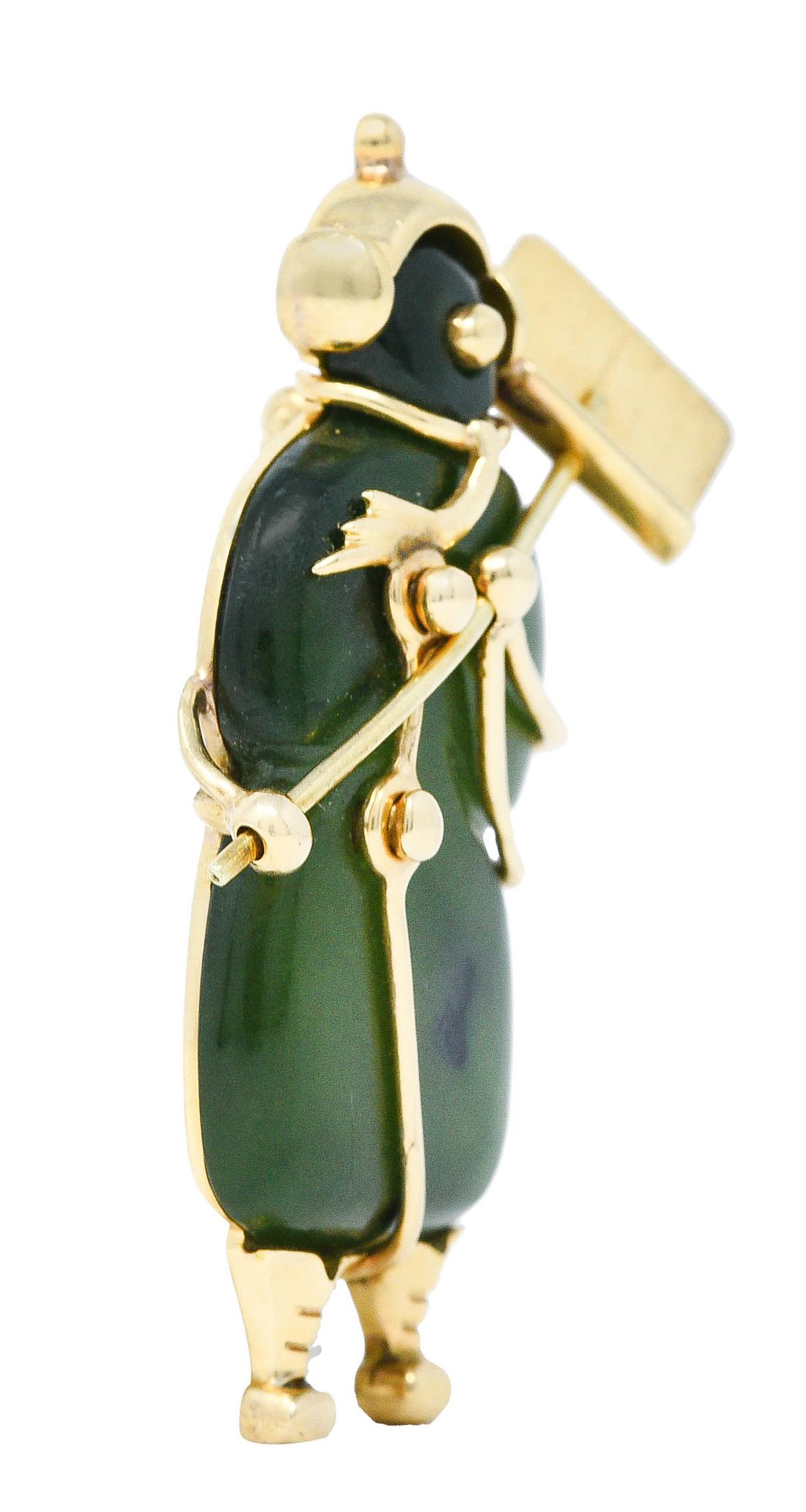 Brooch is comprised of beautifully carved nephrite jade
Translucent green mottled with black in some areas

With a stylized polished gold frame that depicts an earmuffed snowman holding a snow shovel

Completed by a pin stem with locking