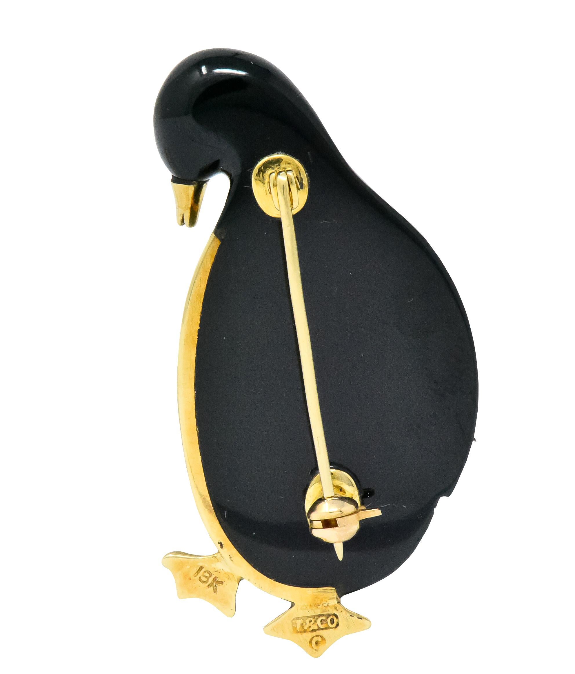Designed as an emperor penguin with carved black jade and mother-of-pearl body

Polished gold webbed feet, beak and detailing

signed T & Co. and stamped 18K

Circa 1970

Measuring: 1 5/8 x 3/4 inches

Total Weight: 12.5 Grams

Adorable. Whimsical.