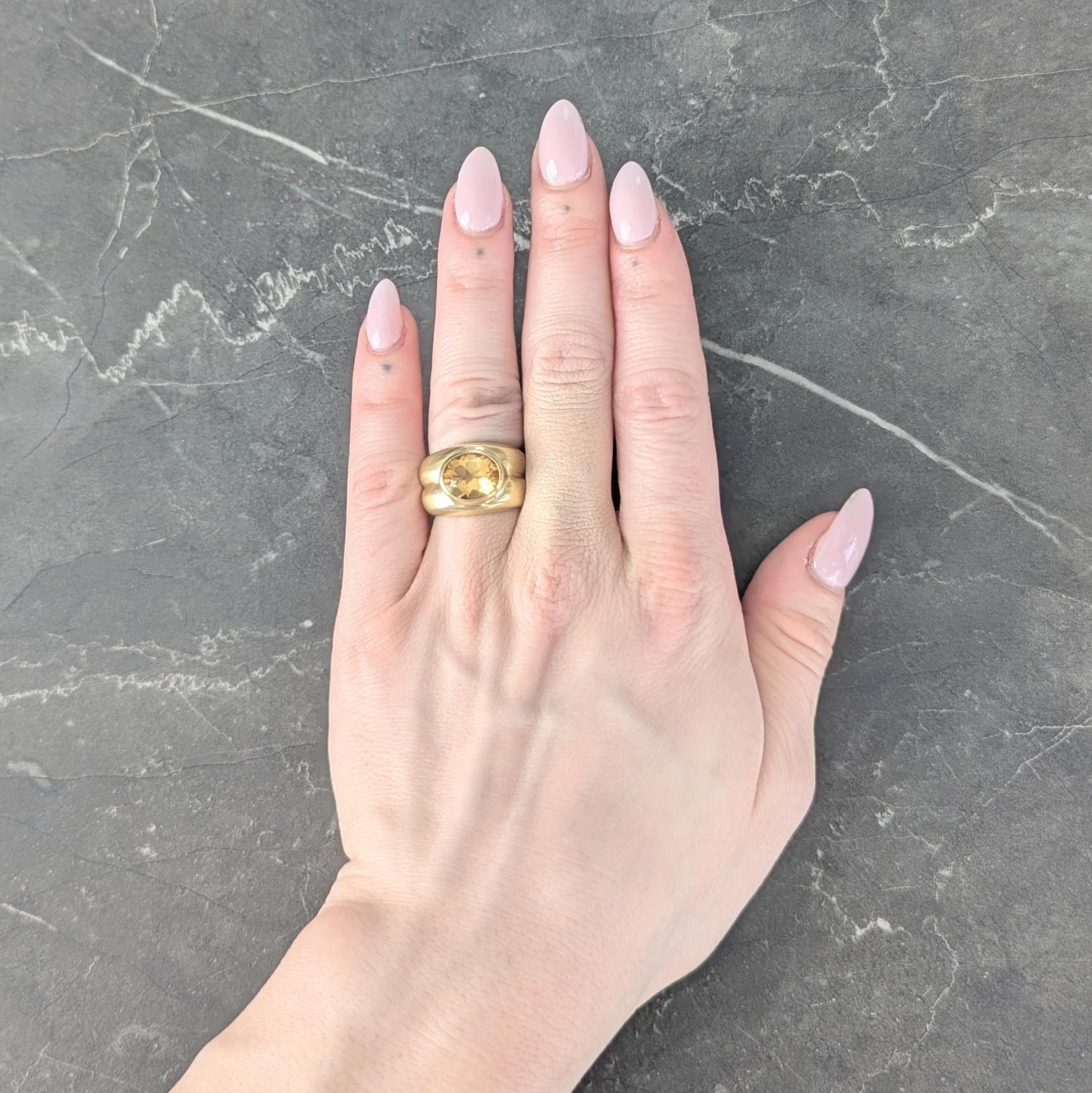 Centering an oval shaped citrine weighing approximately 3.20 carats total
Transparent medium yellowish orange in color and bezel set east to west
Flanked by puffed shoulders with grooved fluted detail
Completed by a matte finish throughout
Stamped