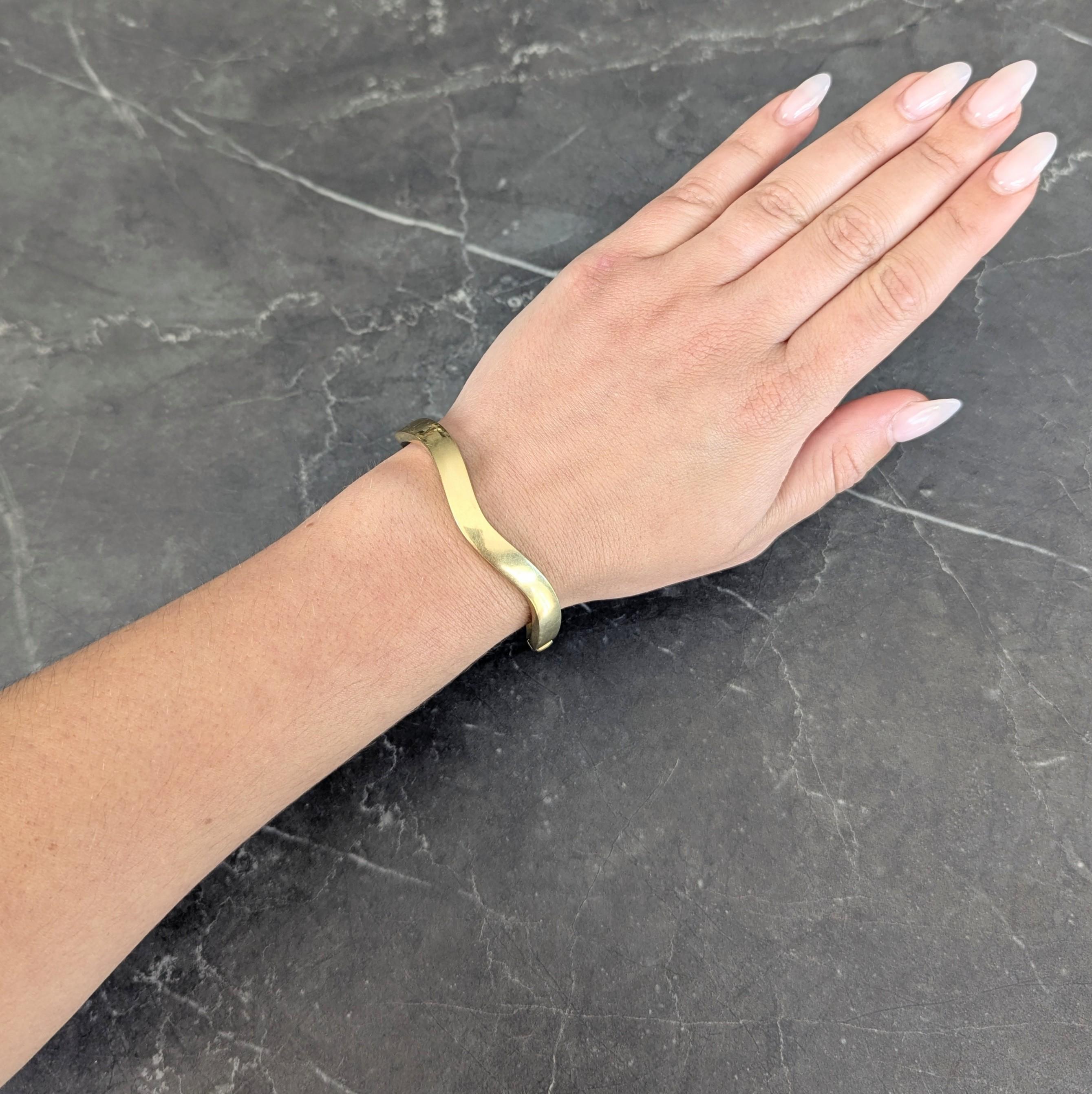 Designed as an oval-shaped bangle with undulating wave motif
With high polish finish
Stamped with Italian assay marks for 18 karat gold
Fully signed for Tiffany & Co., Italy
Circa: 1990s
Width: 1/4 inch
Bracelet Size: 6 3/4 inch circumference with 2