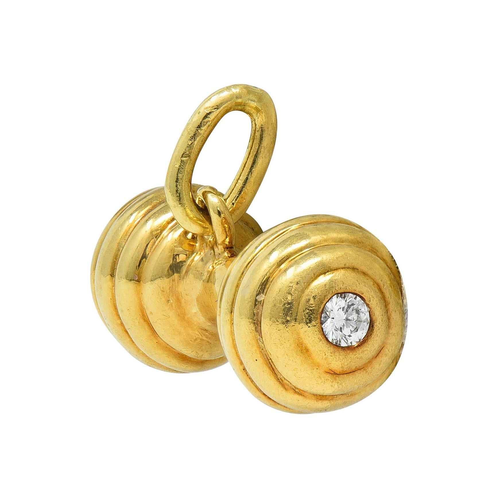 Designed as a stylized barbell style baby rattle with grooved detail
Terminating with grooved baubles with flush set diamonds
Round brilliant cut and weighing 0.10 carat total
Eye clean and bright
Suspending from jump ring bale
Stamped for 18 karat