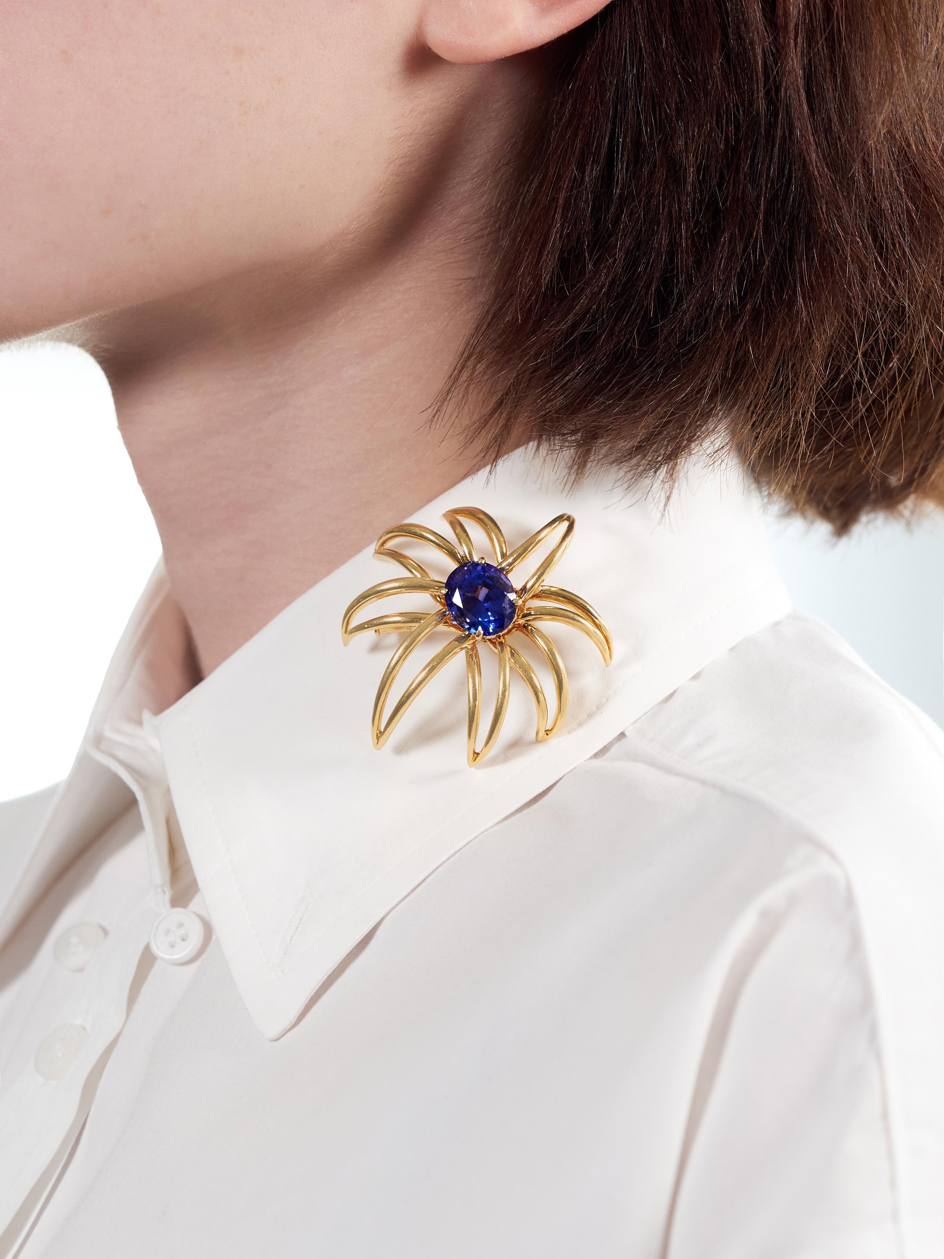 Designed as a stylized firework burst comprised of pierced linear gold
Centering an oval cut tanzanite weighing approximately 10.23 carats total
Transparent medium vibrant blue and prong set in basket
Featuring a high polished finish