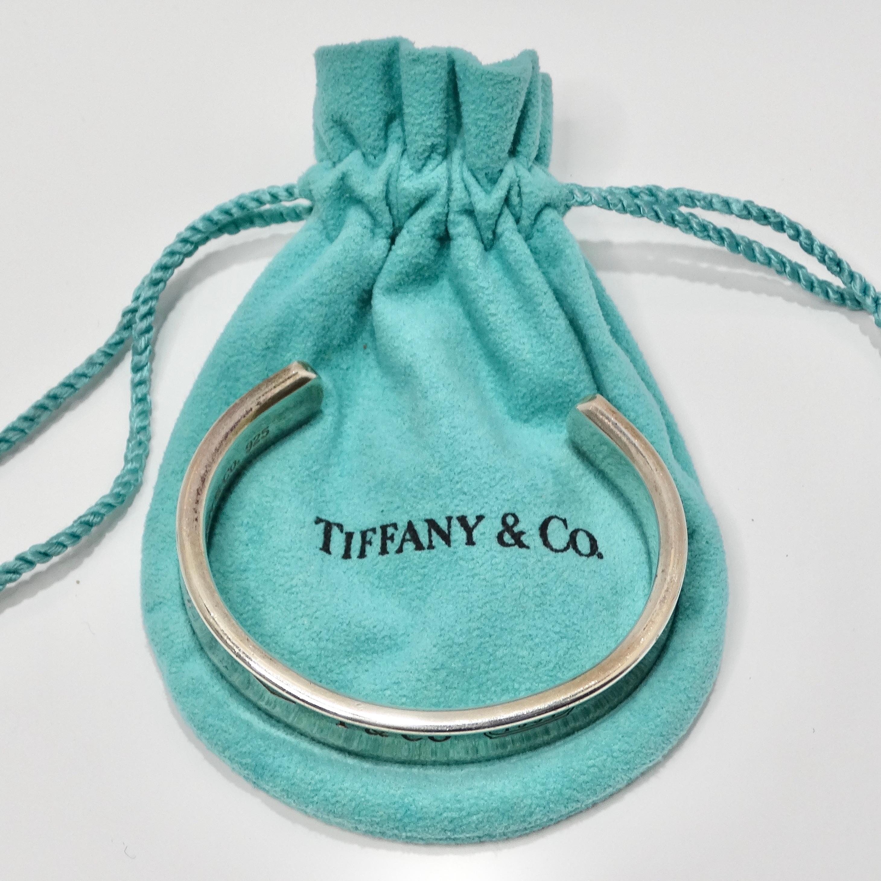 Voici le bracelet manchette en argent 1925 gravé de Tiffany & Co 1997, une pièce intemporelle qui respire l'élégance et la sophistication.

Fabriqué en argent sterling 925 de haute qualité, ce bracelet manchette présente un superbe effet miroir qui