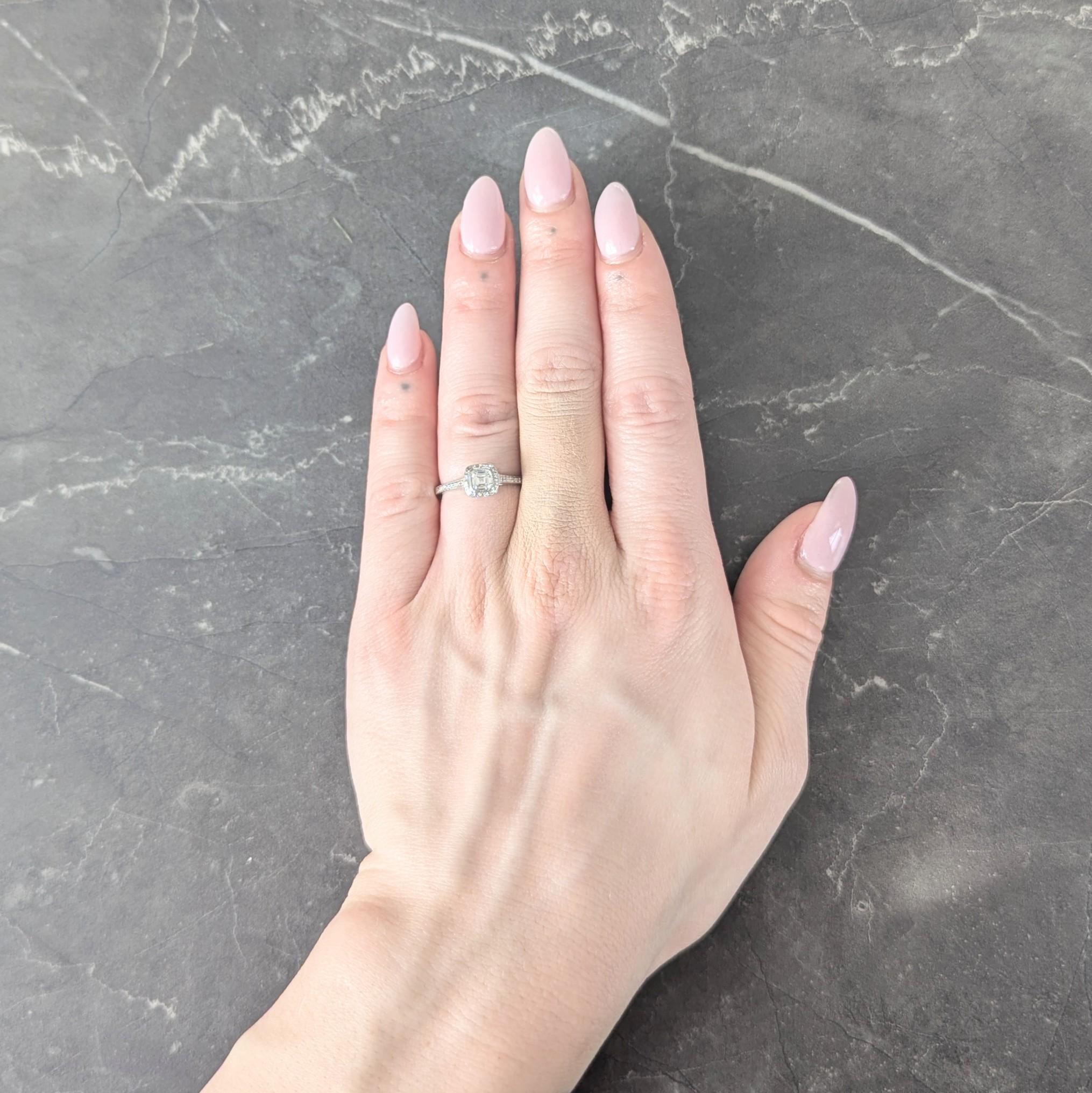 Centering a signature Legacy mixed cushion cut diamond weighing 0.39 carats - G color with VS2 clarity
Bezel set in a pierced 'V' motif basket with halo surround flanked by cathedral shoulders
Bead and bezel set throughout with round brilliant cut