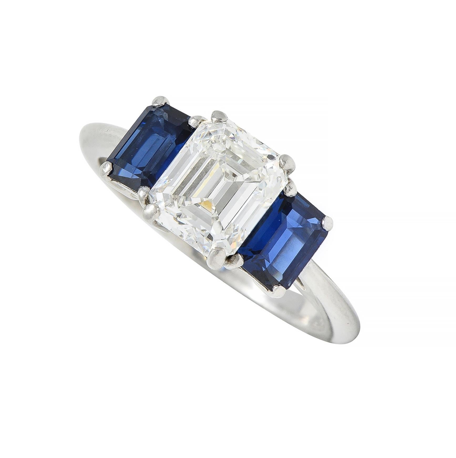 Centering an emerald cut diamond weighing 1.59 carats - G color with VS2 clarity
Prong set in basket and flanked by emerald cut sapphires
Weighing approximately 1.12 carats total - prong set
Transparent medium blue in color 
Flanked by cathedral