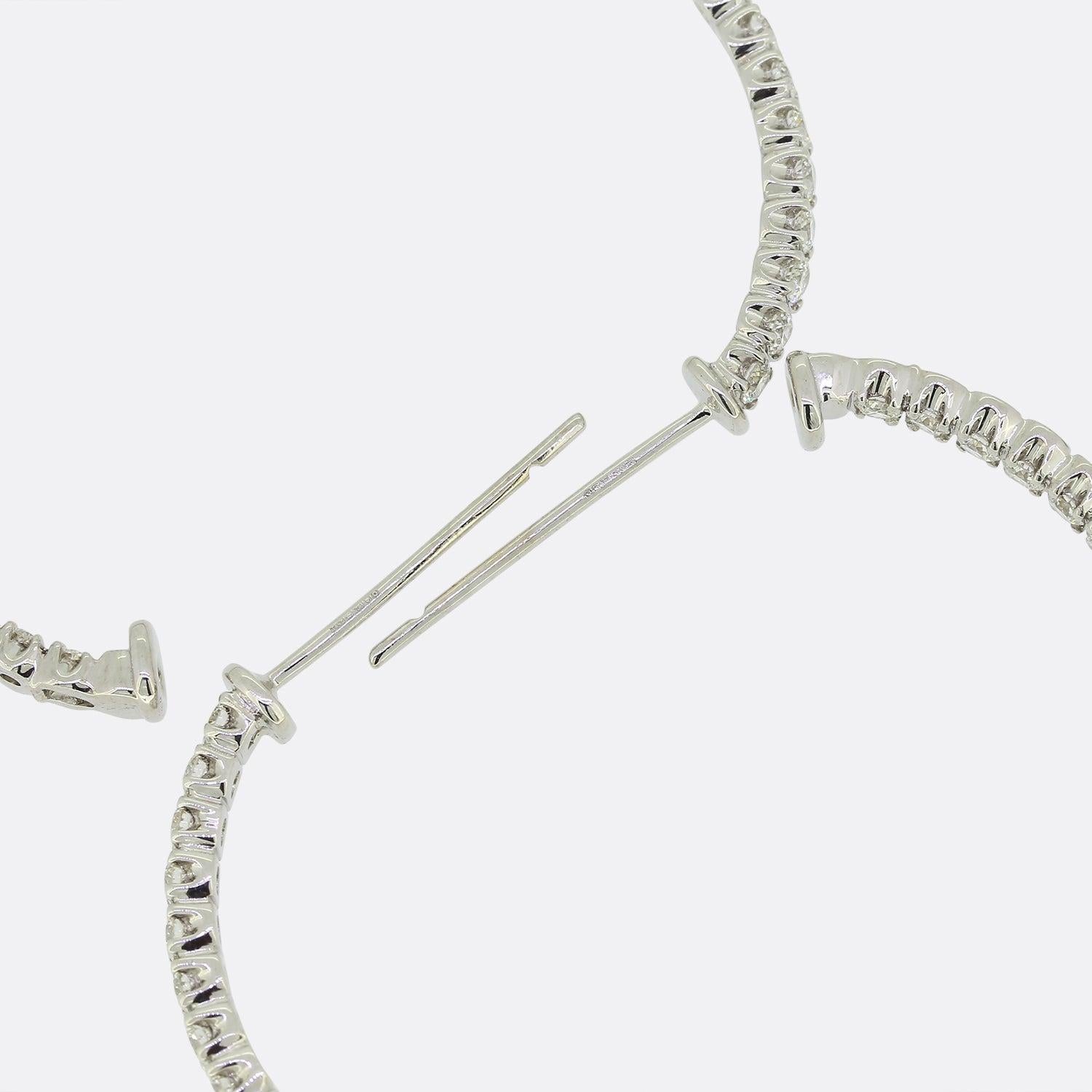 This is a pair of 18ct white gold diamond hoop earrings from the luxury jewellery designer, Tiffany & Co. These earrings have been cleverly made in two halves with a hinge at the base, joining the two together. They are set with round brilliant cut