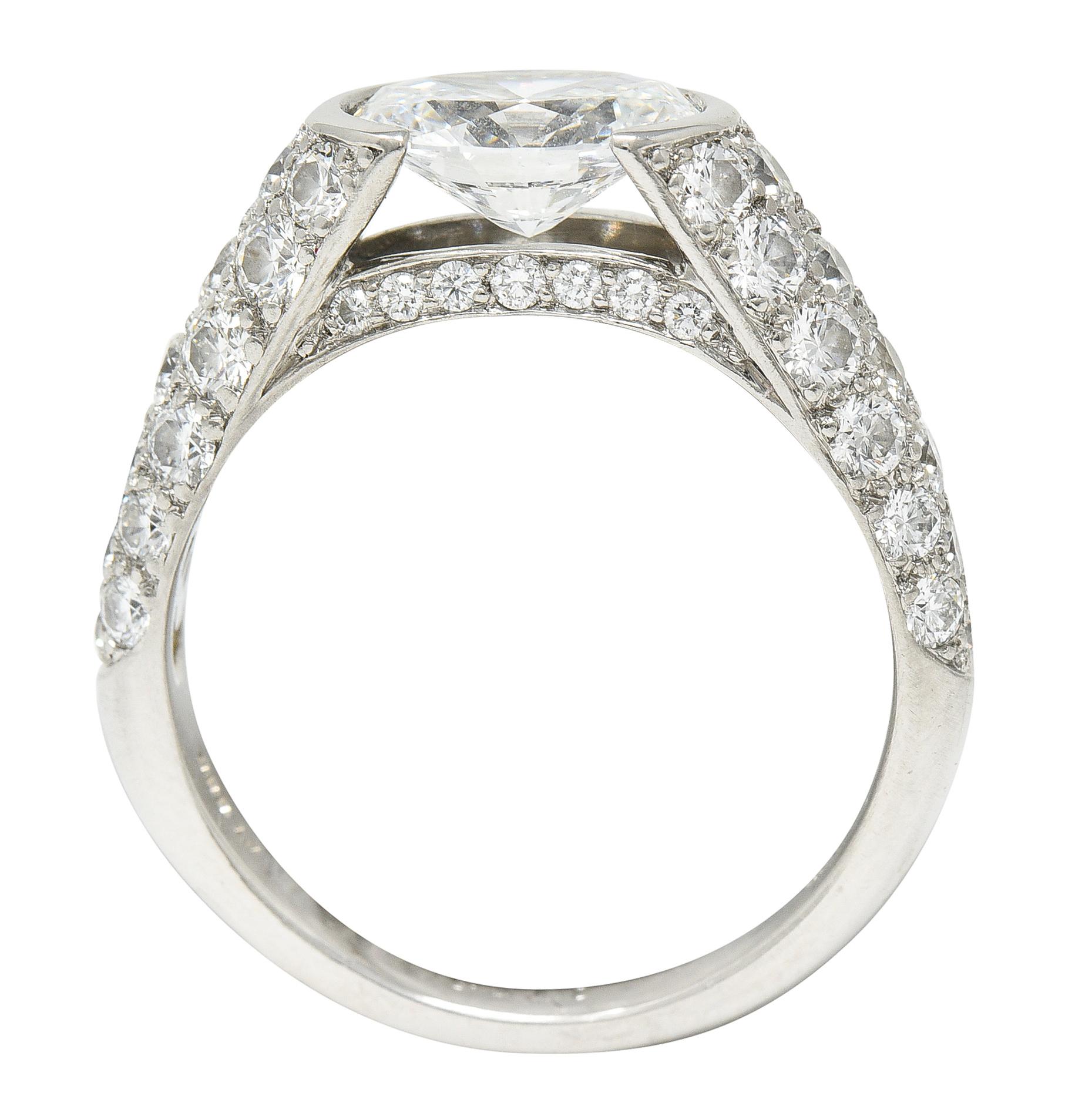Featuring an oval cut diamond weighing 1.44 carat - E color with VVS2 clarity. Half bezel set East to West with dramatic cathedral shoulders. Pavè set with round brilliant cut diamonds. Weighing collectively approximately 2.00 carats - F/G color