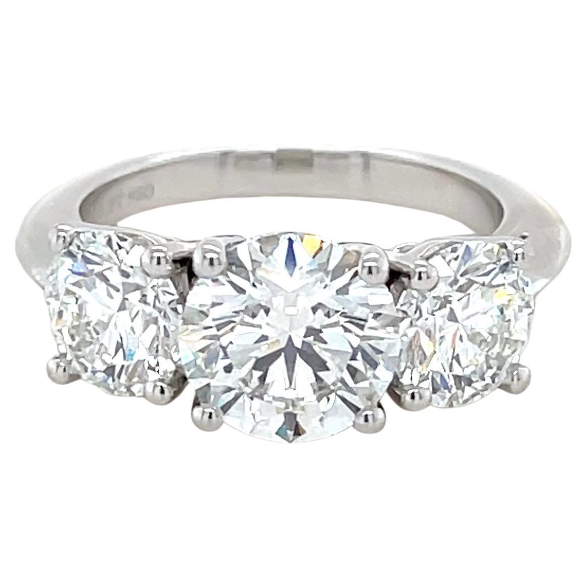 This beautiful three stone engagement ring crafted by Tiffany & Co. boasts one center round brilliant cut diamond weighing 1.90 carats with G color, VVS2 clarity and Triple Excellent cut, polish and symmetry, flanked by two round brilliant cut