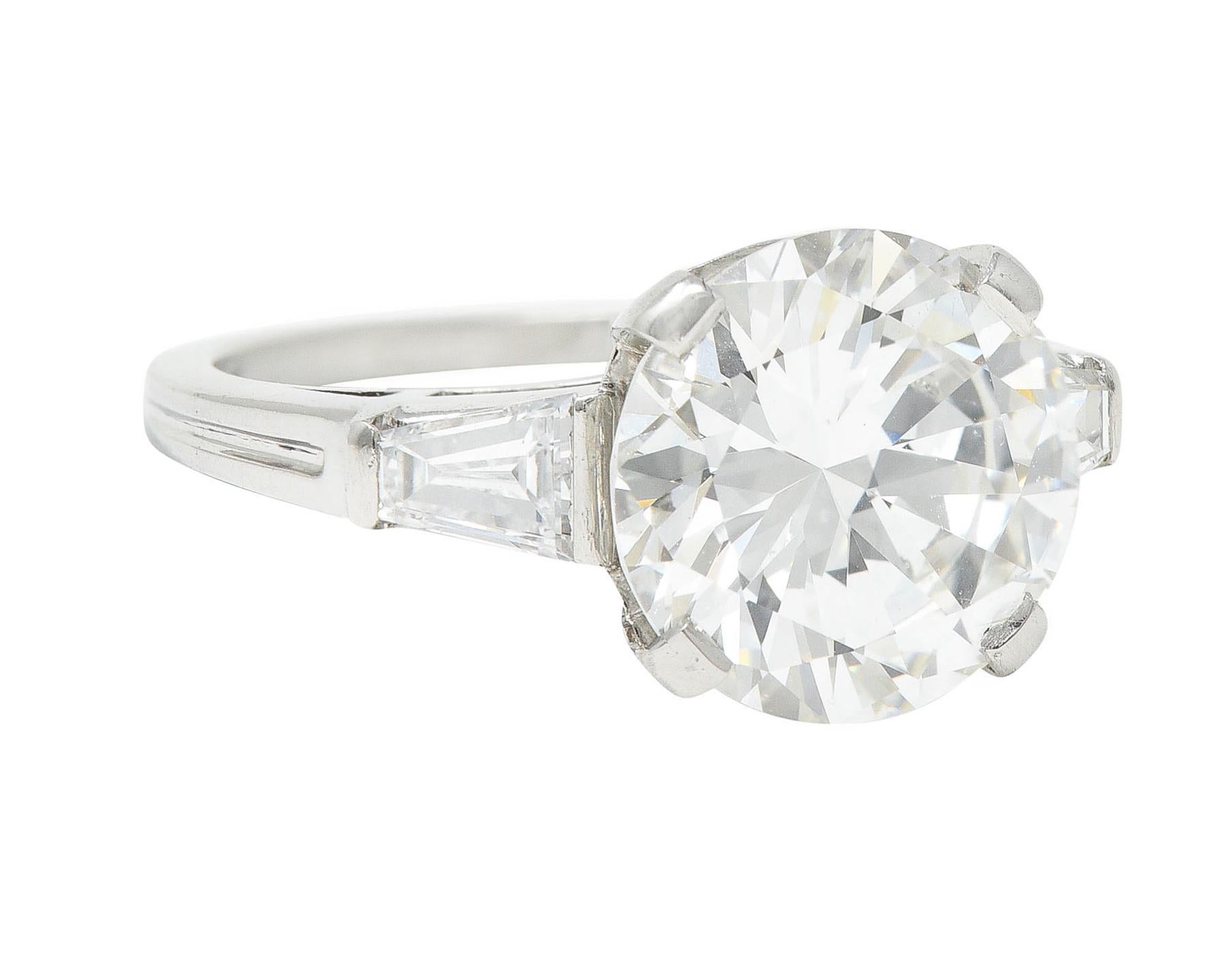 Featuring a round brilliant cut diamond weighing 3.59 carats - I color with SI1 clarity

Basket set by wide prongs and flanked by cathedral shoulders

Bar set by tapered baguette cut diamonds weighing approximately 0.35 carat total - well matched to