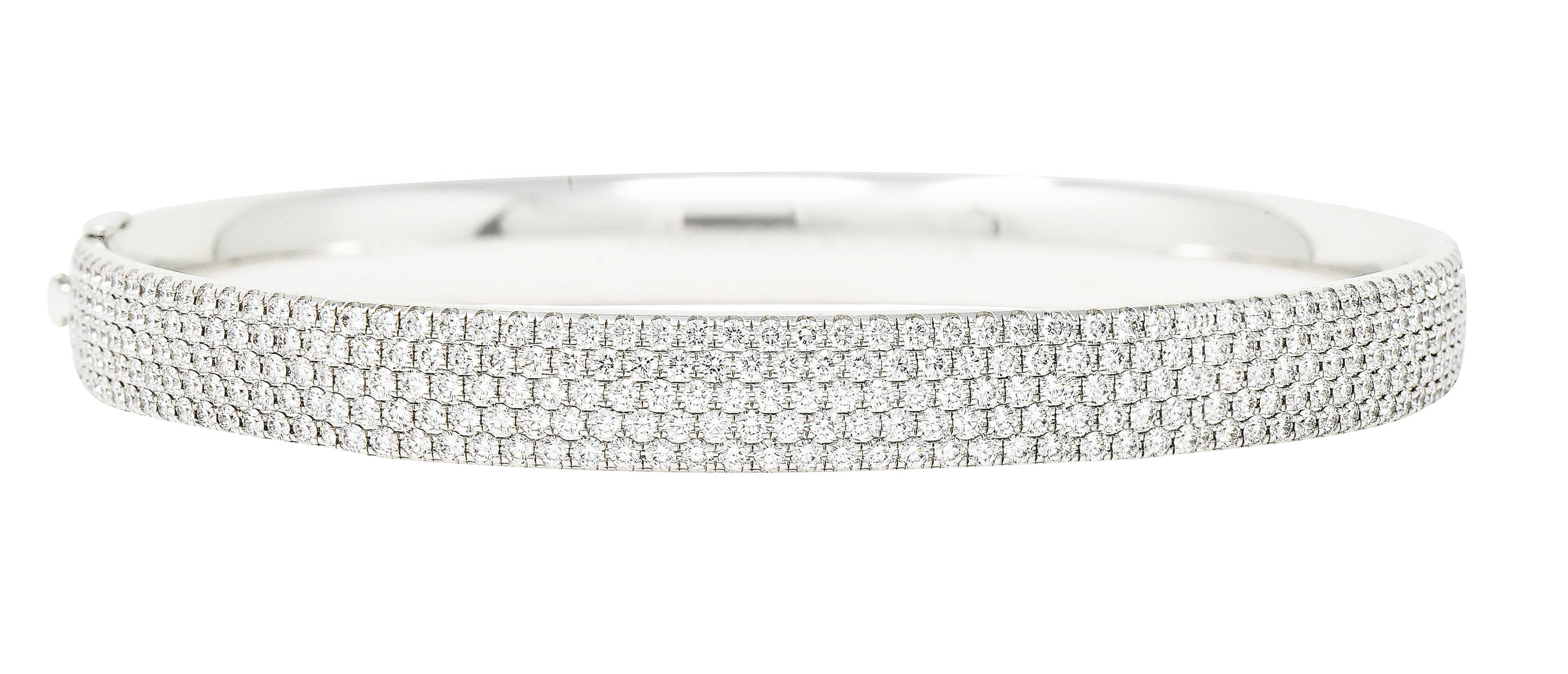 Hinged bangle bracelet is pavè set to front by five rows of round brilliant cut diamonds. Weighing collectively approximately 4.96 carats with F/G color and overall VS clarity. Completed by a concealed clasp with secure fold-over safety. Stamped