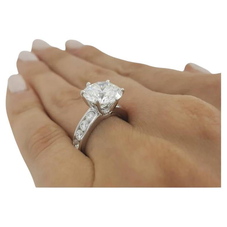 Tiffany & Co. Channel-Set Diamond Ring featuring a magnificent 5.00 ct round brilliant cut center diamond. The ring weighs 9.6 grams and is size 6. The center diamond is a natural round brilliant cut diamond weighing 5.00 ct, with a color grade of H