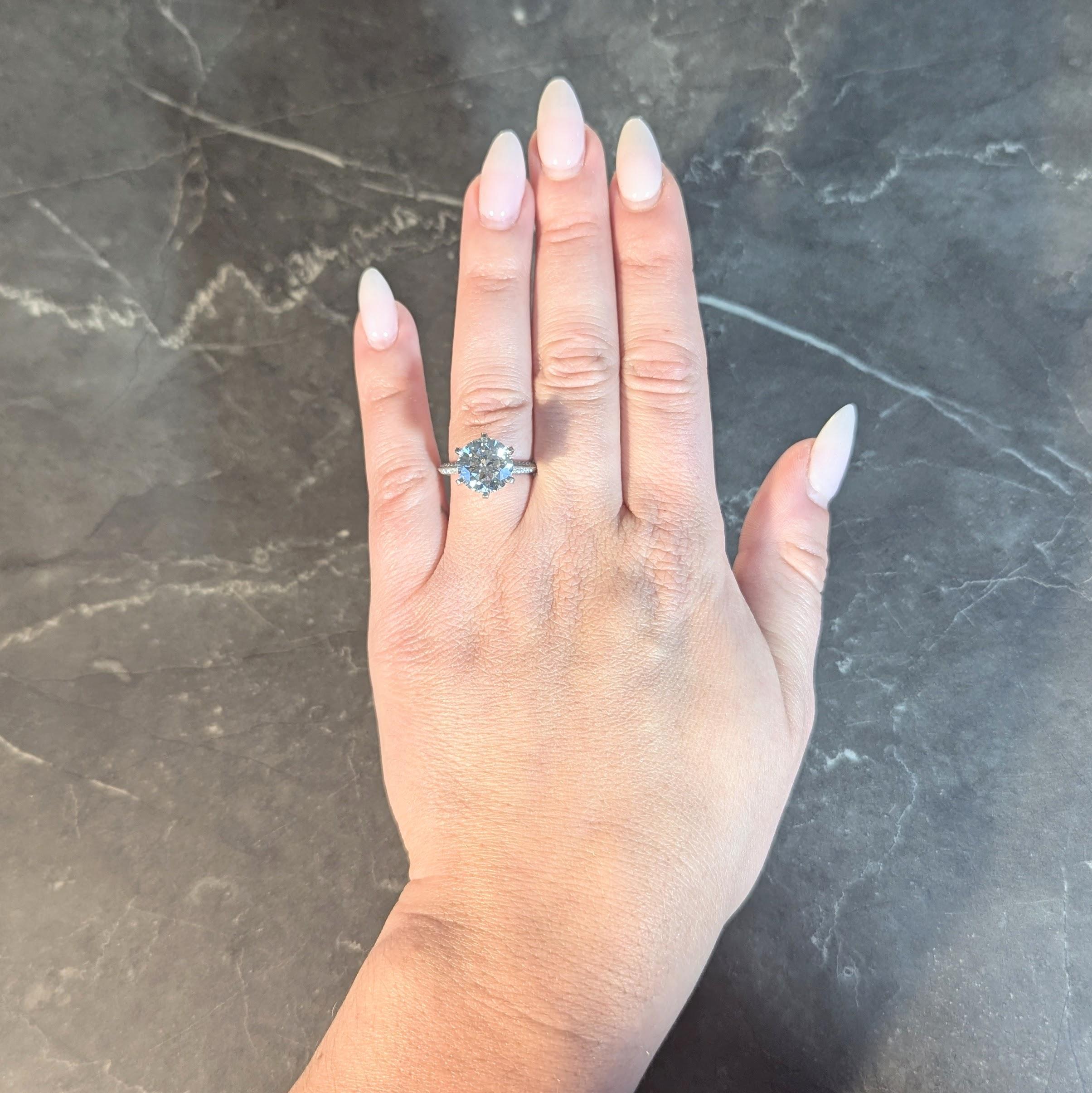 Centering a round brilliant cut diamond weighing 4.26 carats - I color with VS1 clarity
Set in a classic Tiffany six pronged mount flanked by knife edge shoulders
Pavé set throughout with round brilliant cut diamonds
Weighing approximately 1.20