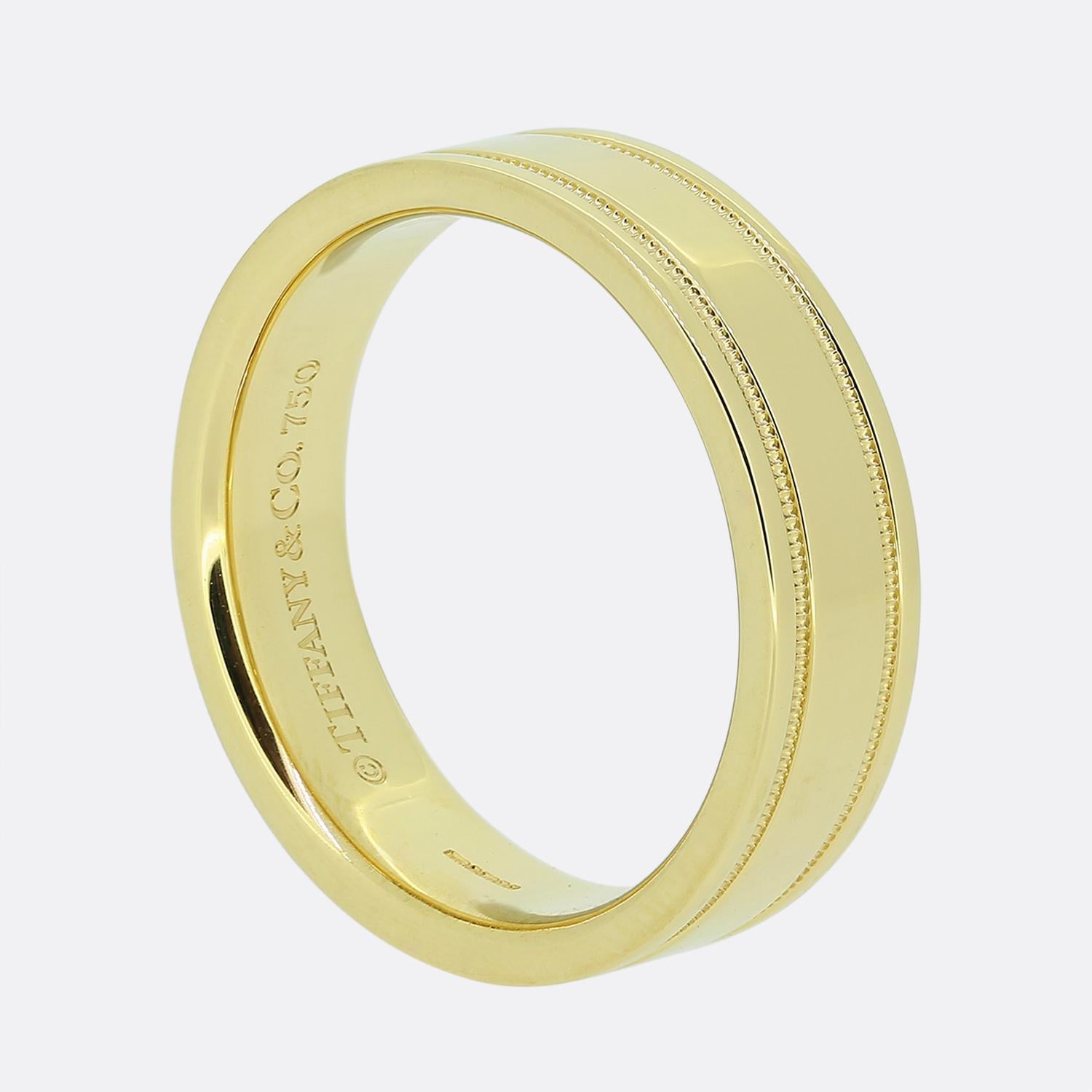 Here we have a classic wedding band ring from the world renowned jewellery designer, Tiffany & Co. This piece has been crafted from 18ct yellow gold, is 6mm in width and showcases a timeless two row milgrain design with a plain polished
