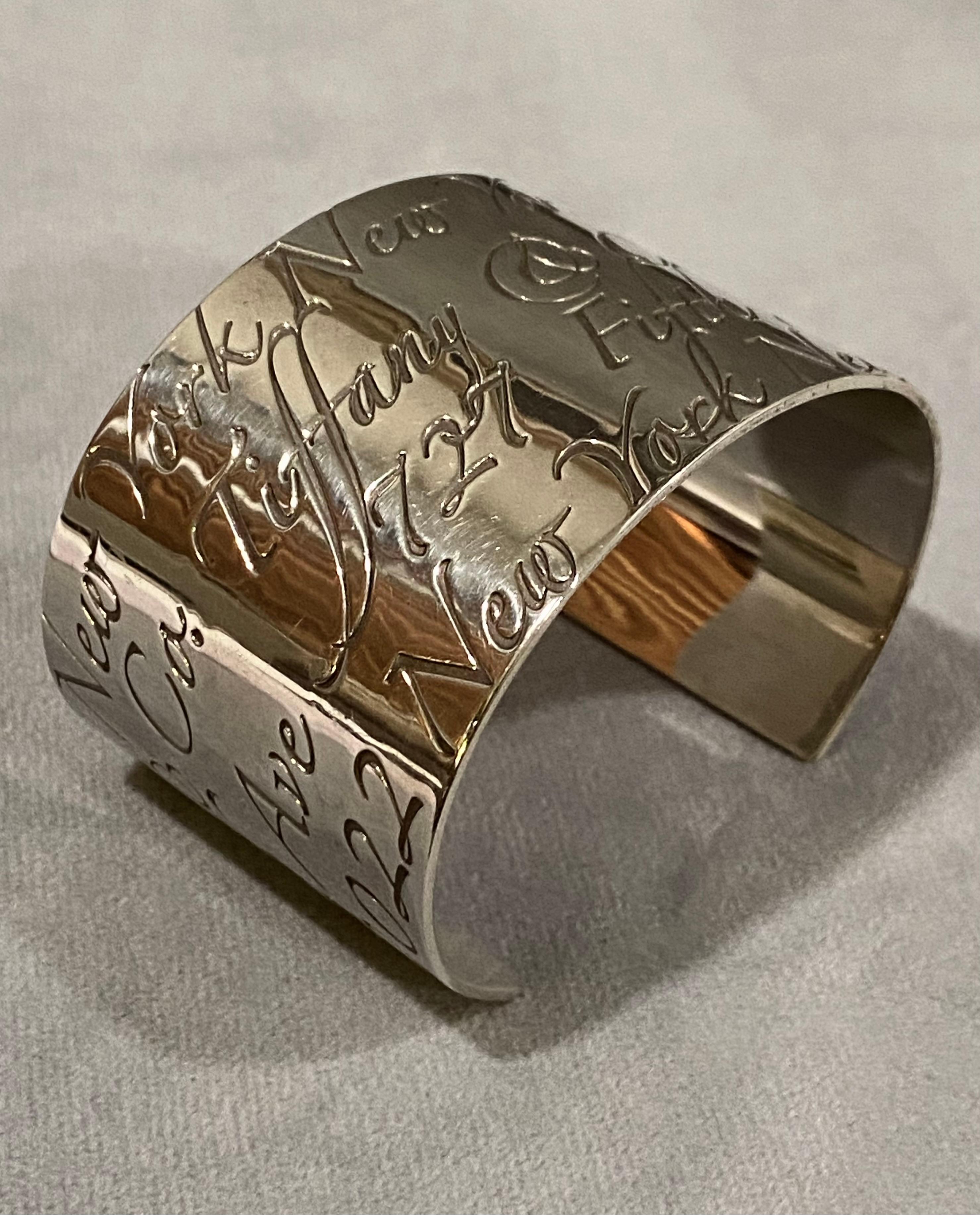 This iconic cuff bracelet design by Tiffany & Co. in sterling silver is part of the Notes collection. It is designed with repeating script that reads 'Tiffany & Co 727 Fifth Ave New York'. The Notes collection highlights the flagship store address