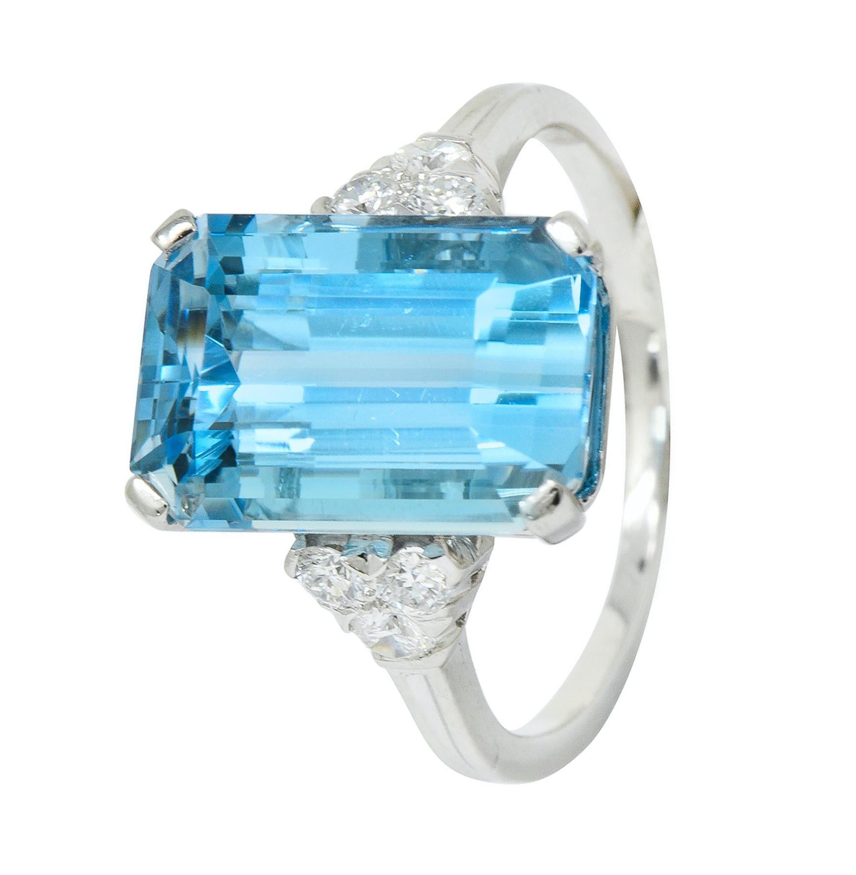 Centering a basket set emerald cut aquamarine weighing approximately 7.08 carats, transparent and a vivid sky blue color

Flanked by triangular formations of round brilliant cut diamonds weighing in total approximately 0.30 carat, F/G color and VVS