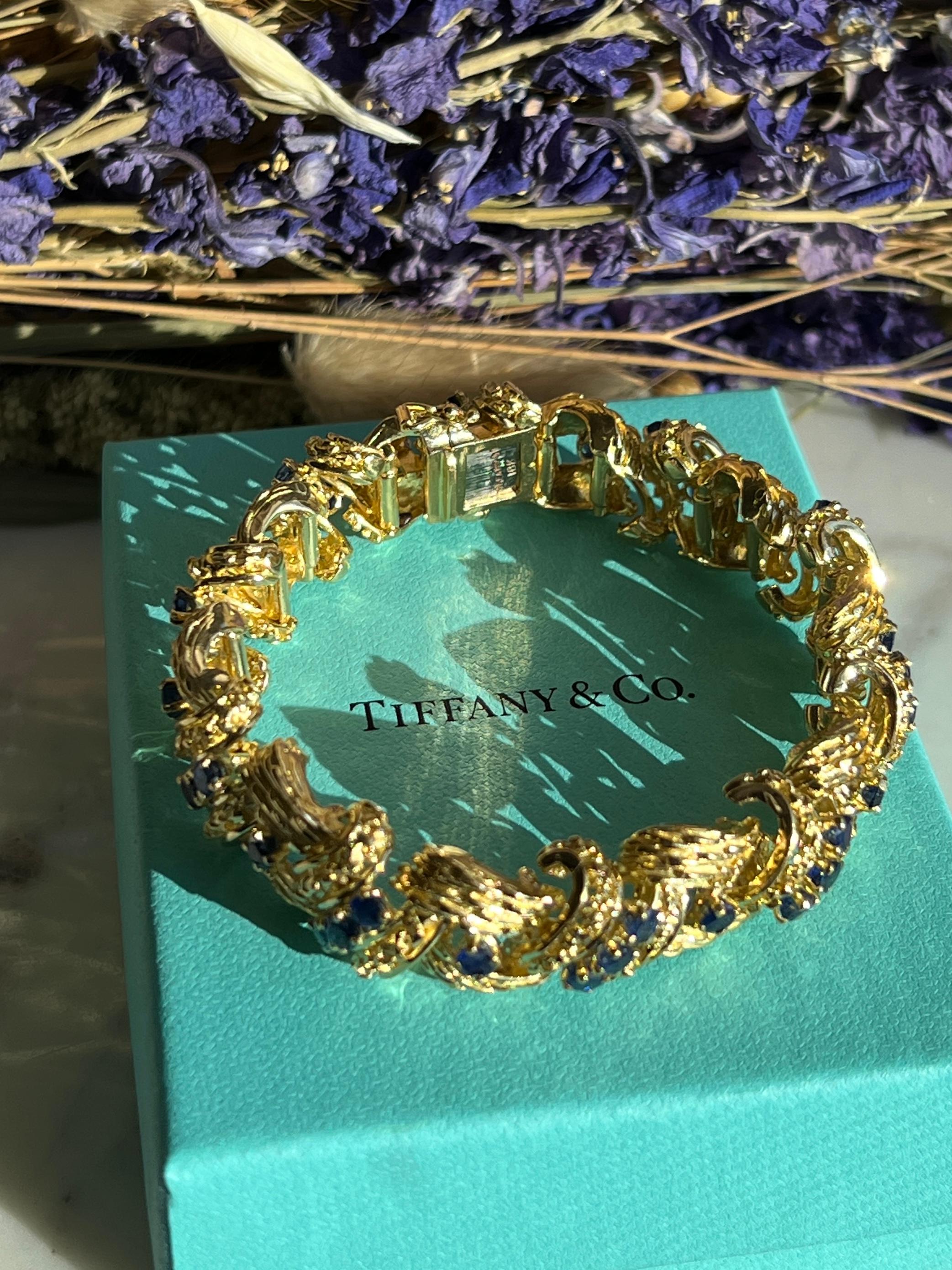 Indulge in timeless elegance with this Tiffany & Co. 18-karat yellow gold bracelet. Its intricate woven design is adorned with forty vibrant round blue sapphires, totaling approximately 8.80 carats. Measuring 7.5 inches in length, the bracelet is