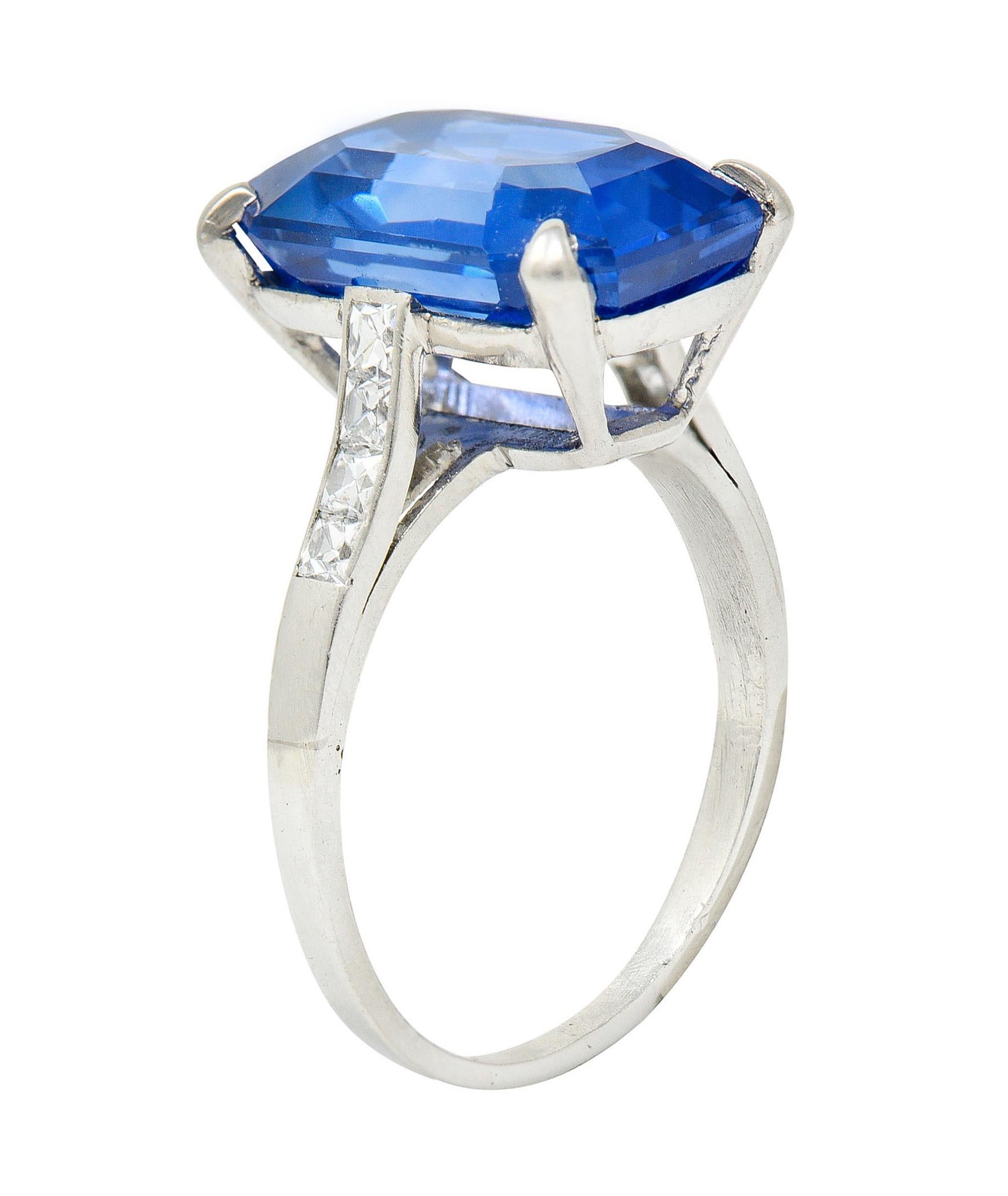 Centering an emerald cut Ceylon sapphire weighing 9.00 carats

Transparent with strong cornflower blue color and no indications of heat - Sri Lankan in origin

Basket set and flanked by cathedral style shoulders accented by French cut