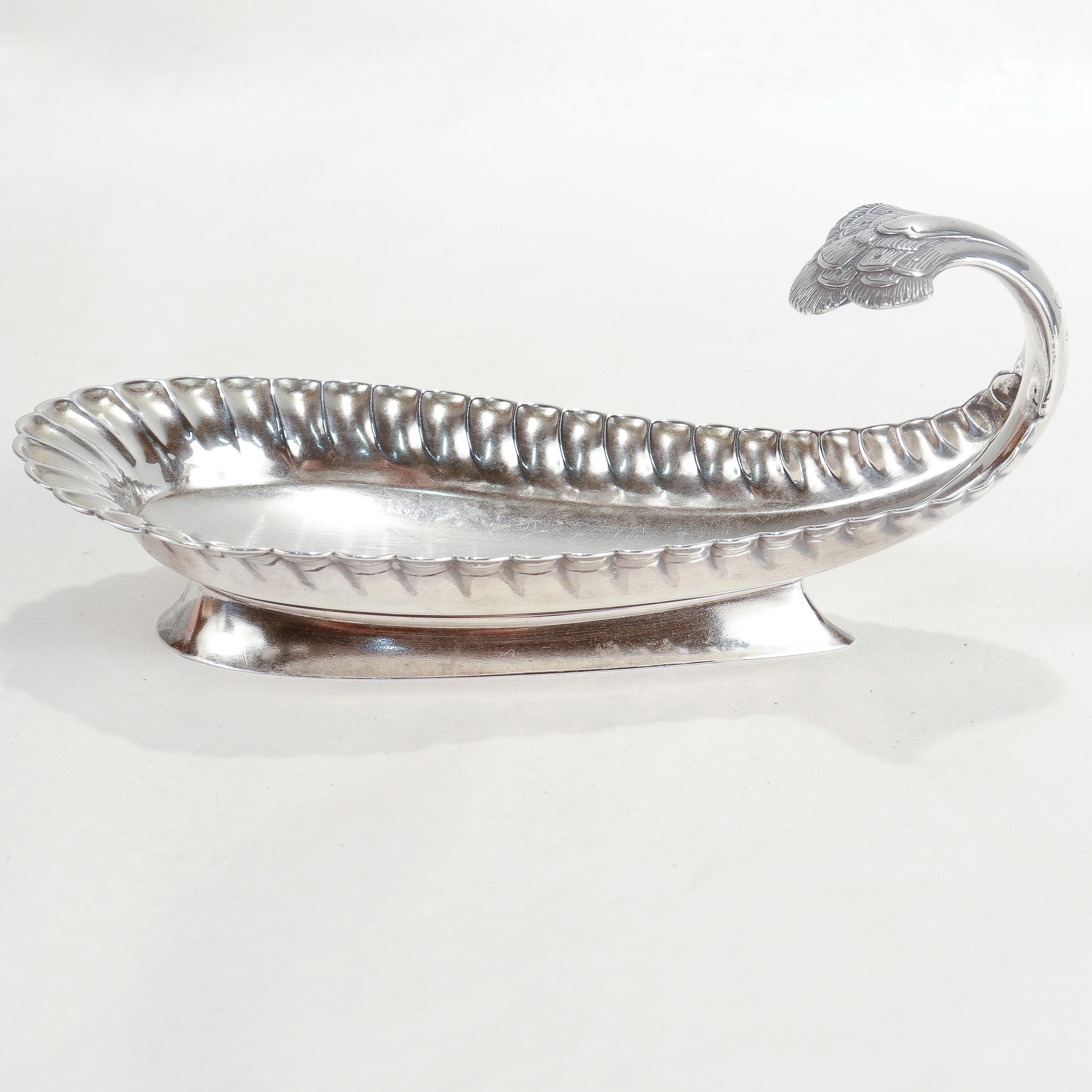 A fine small-scale Aesthetic Movement period footed or handled bowl.

By Tiffany & Co.

In sterling silver.

In the form of a stylized peacock feather with a curved handle. Decorated further with stippled peacock decoration to the handle.

Simply a