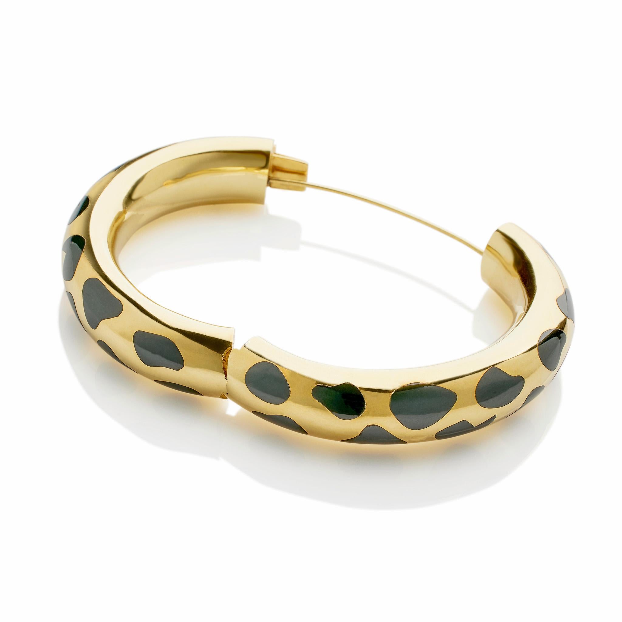 Created by Tiffany & Co. in the 1970s, this 18K gold and black jade bracelet was designed by Angela Cummings. The hinged, polished 18K gold bangle is inlaid with irregular spots of black jade resembling a leopard skin that are flush with the curved