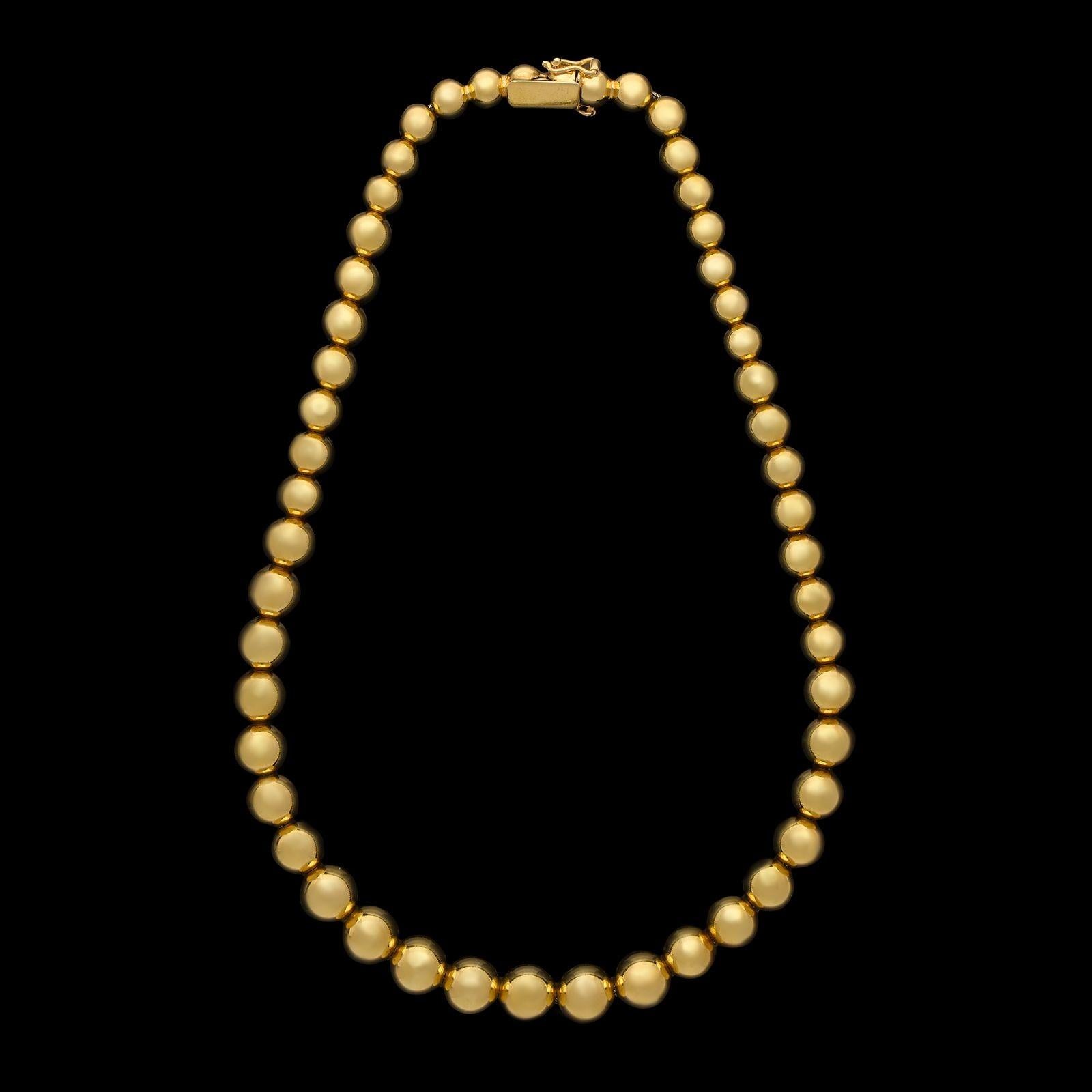 An 18ct gold bead necklace by Tiffany & Co, circa 1980s, the 16” necklace formed of fifty round gold highly polished beads, graduating smaller in size from front to back, all threaded onto a foxtail-link chain, making the necklace highly flexible,