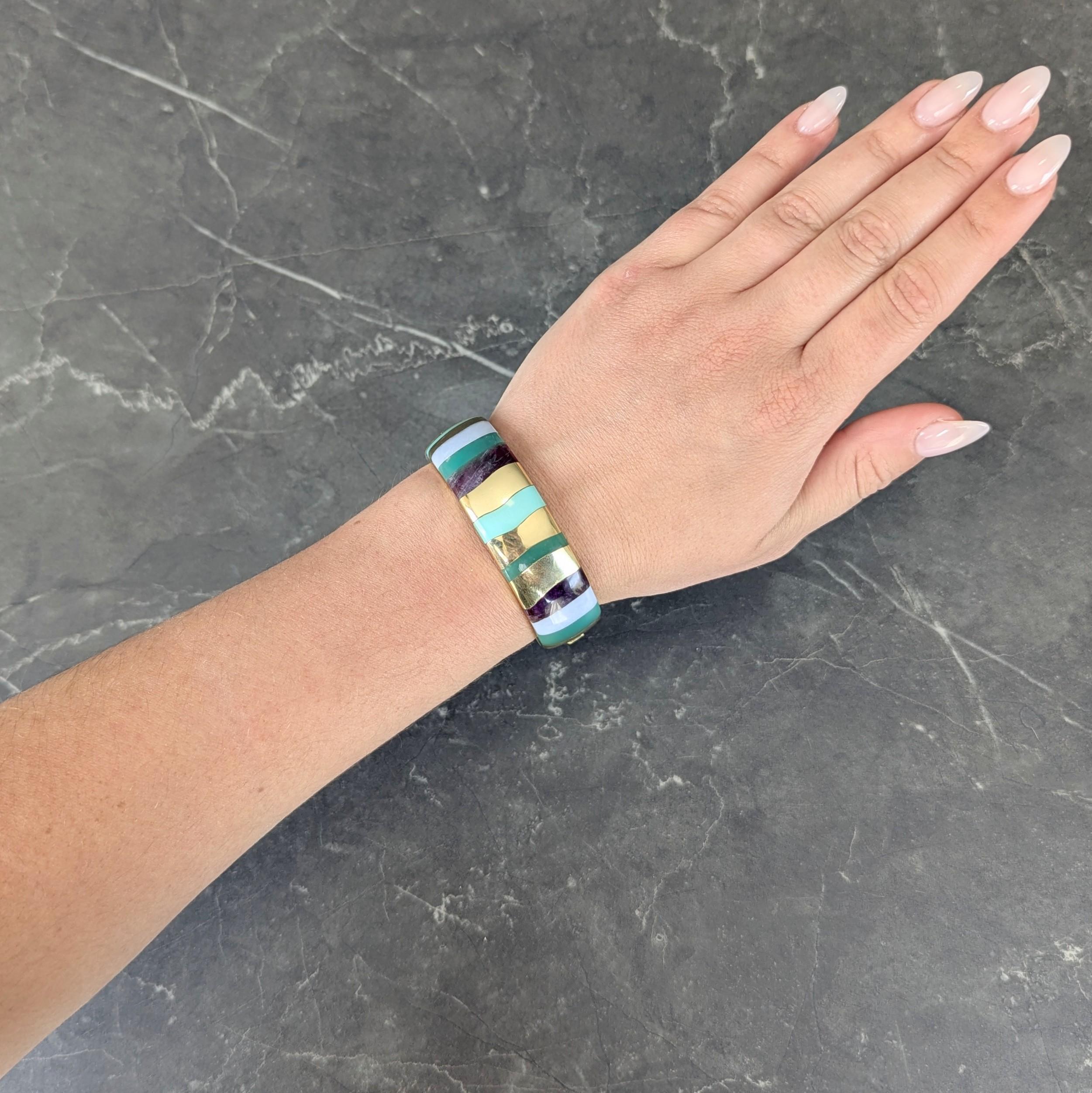 Designed as a wide bangle bracelet with curved surface inlaid with wavy stripe pattern
Featuring amethyst, various chalcedony, and turquoise alternating with gold stripes
Transparent purple, opaque pastel green, opaque pastel blue, and greenish blue
