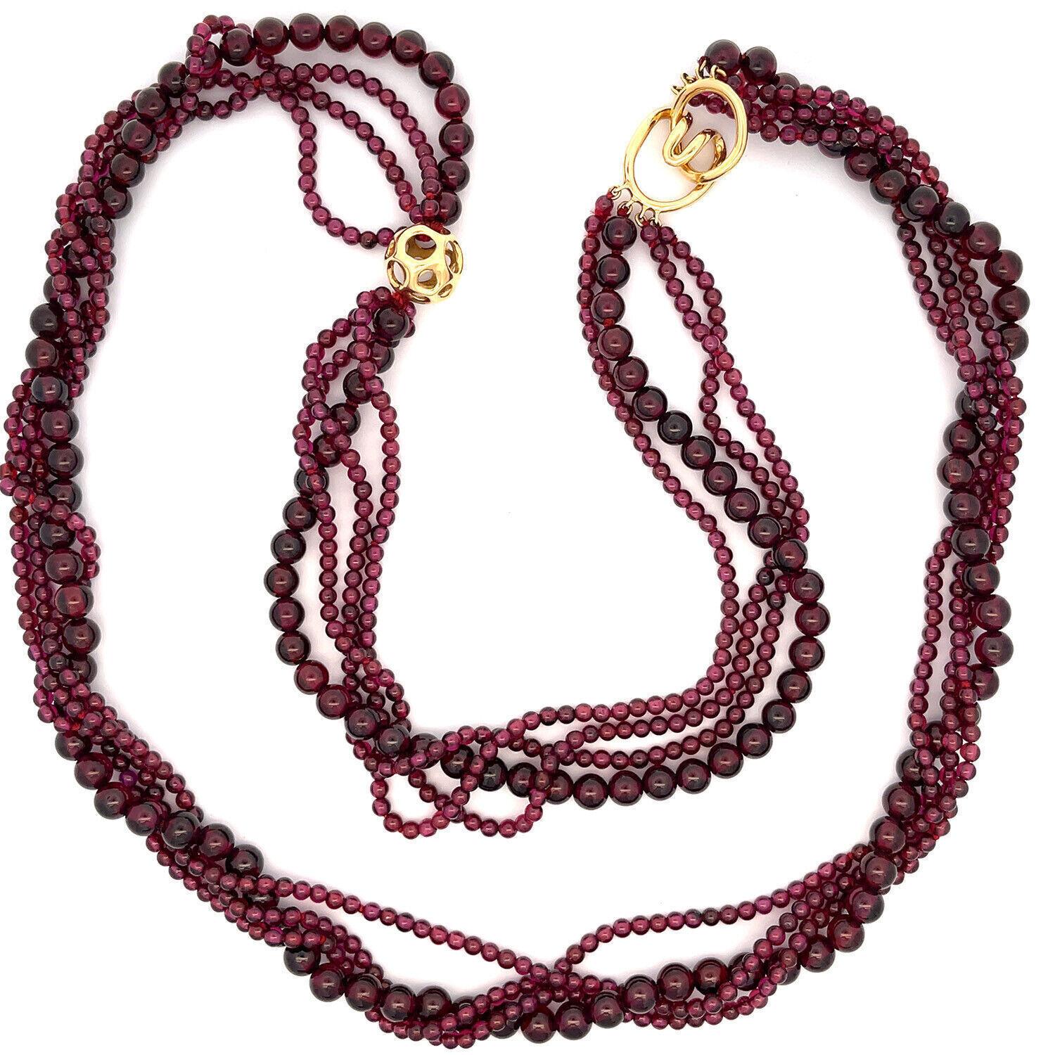 From Tiffany & Co. by designer Angela Cummings, this long elegant necklace has 4 strands garnet beads, 3 strands small beads, the 4th strand has larger beads. It is accented with a 13mm open style gold ball and it secure with a ring and hook clasp