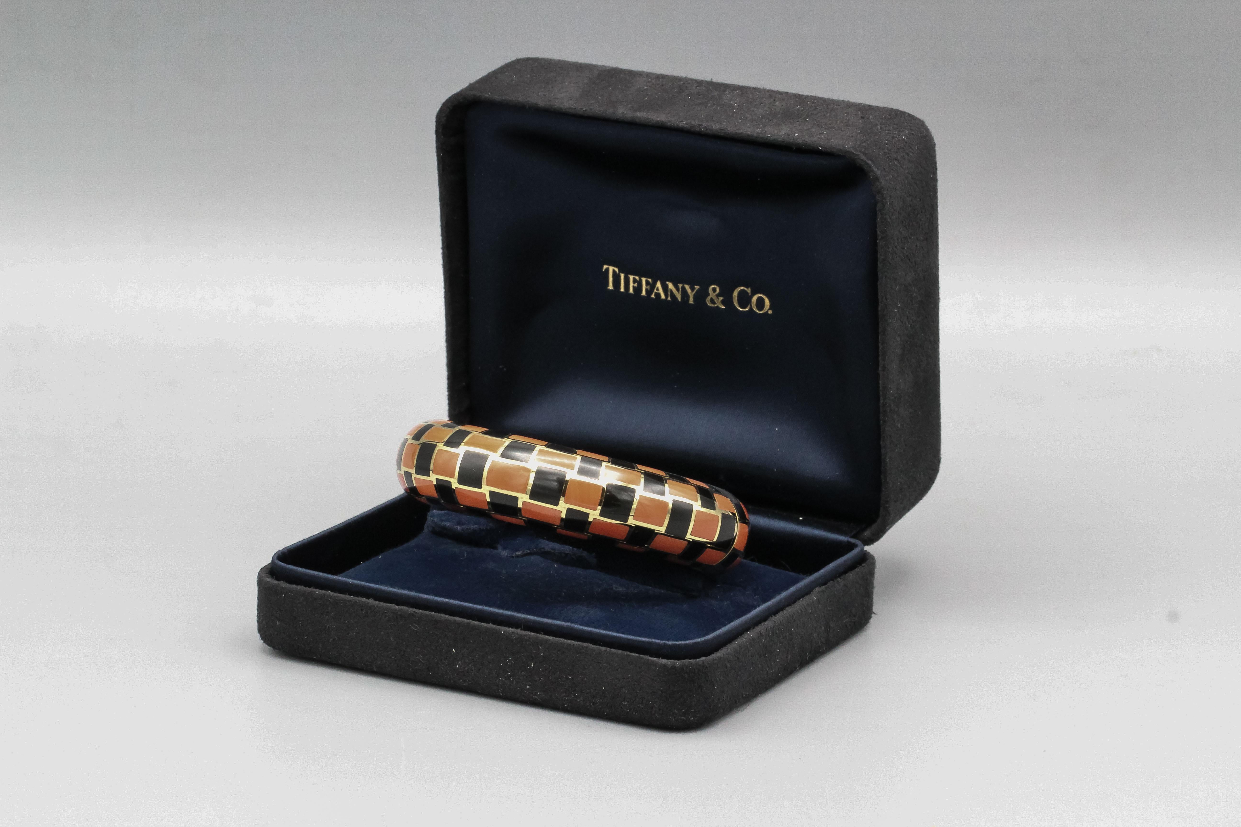 Very fine 18K yellow gold bangle bracelet with inlaid coral and black jade, by Tiffany & Co. designed by Angela Cummings circa 1970s. It features a chic  checkered pattern that is stylish and distinctive.  Will comfortably fit a 6-6.25