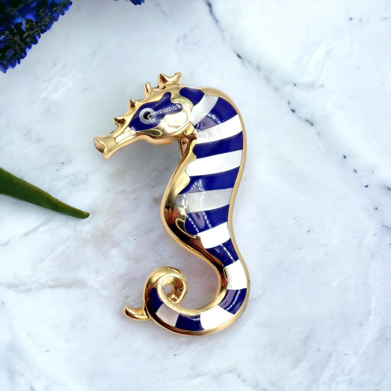 This vintage 1970's Tiffany & Co. brooch, designed by the iconic Angela Cummings, is a captivating work of art.  

Exquisitely crafted in 18k yellow gold, it presents a large seahorse motif, intricately adorned with deep blue lapis and luminous