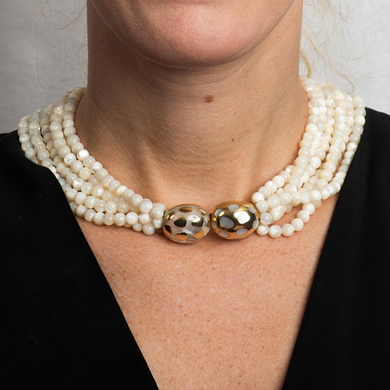 This beautiful and unique necklace by Angela Cummings for Tiffany & Co. features six strands of mother of pearl beads with an 18 karat yellow gold clasp. The clasp features mother of pearl inlaid in an opposite pattern. Box clasp. 
Measurements: