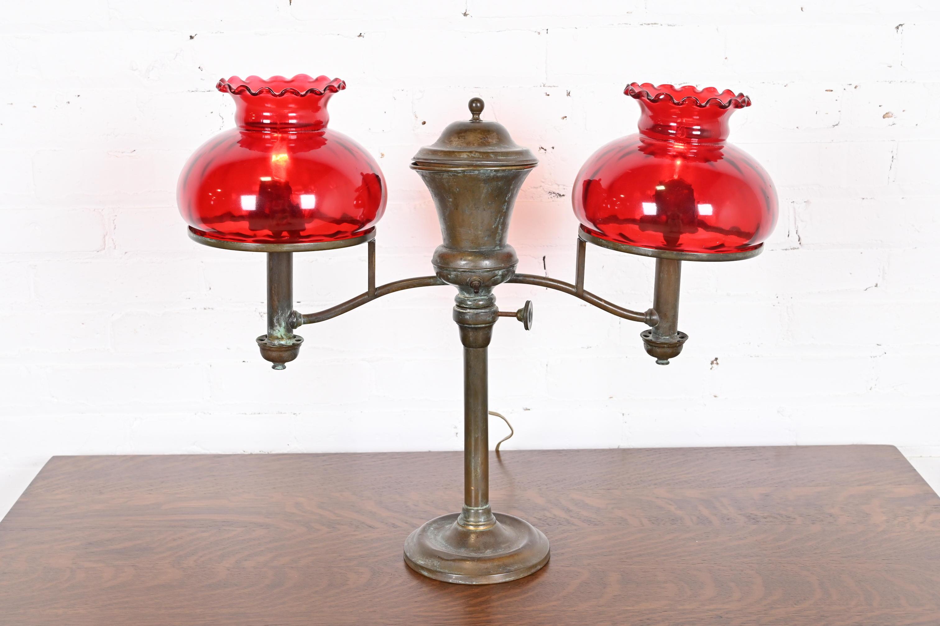 Hervorragende Doppelarm-Schreibtischlampe aus der Zeit des Arts & Crafts oder Art Deco

Von Hinrichs of New York und vertrieben von Tiffany & Co.

New York, USA, Ende des 19. Jahrhunderts

Bronze, mit schönen roten Kunstglasschirmen.

Maße: 23 