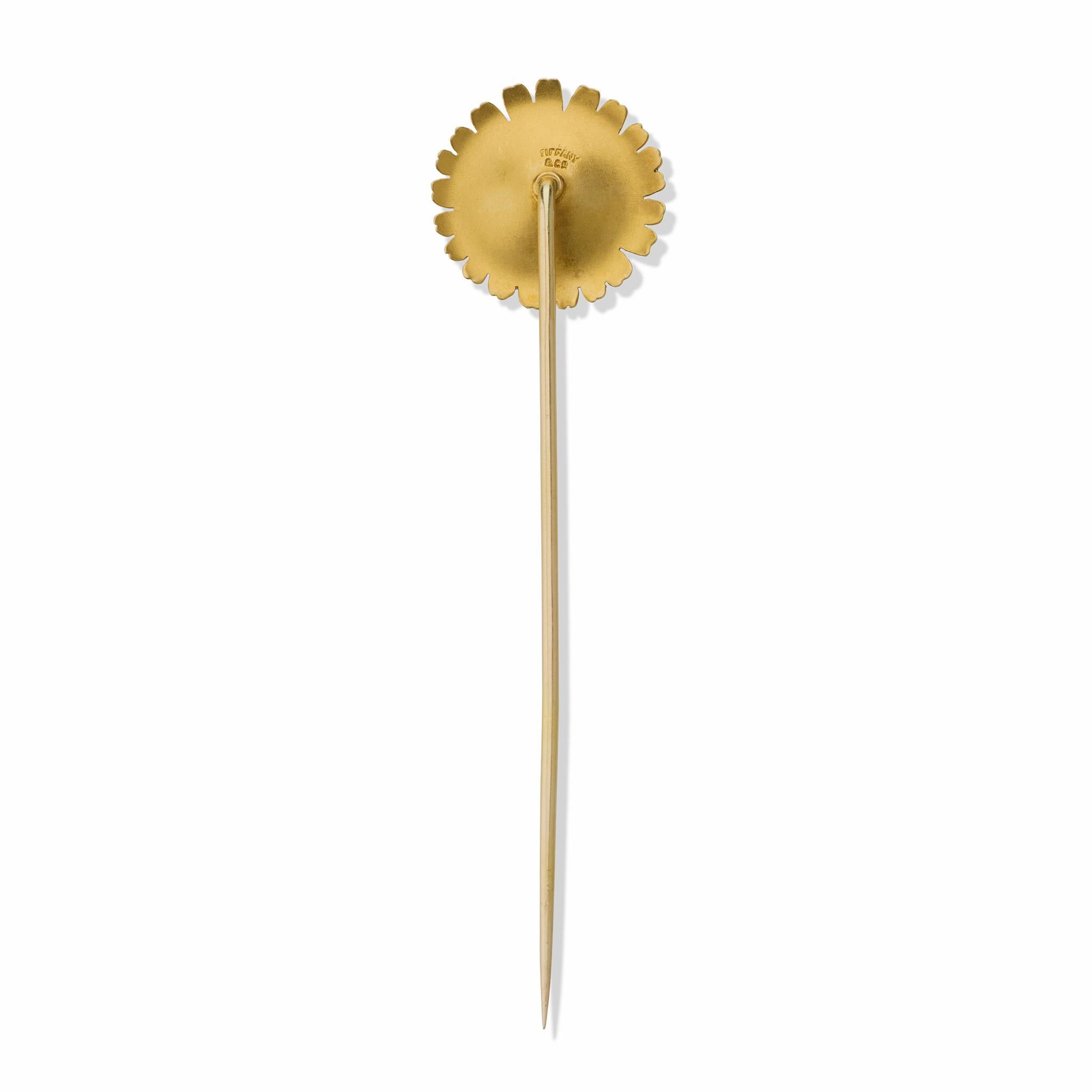 Created circa 1900, this Tiffany & Co. daisy stick pin is composed of 18K gold and enamel. It is designed as a full white en plein enamel blossom with pale blue tones and a textured gold center. Naturalistic and elegant, this pristine little jewel