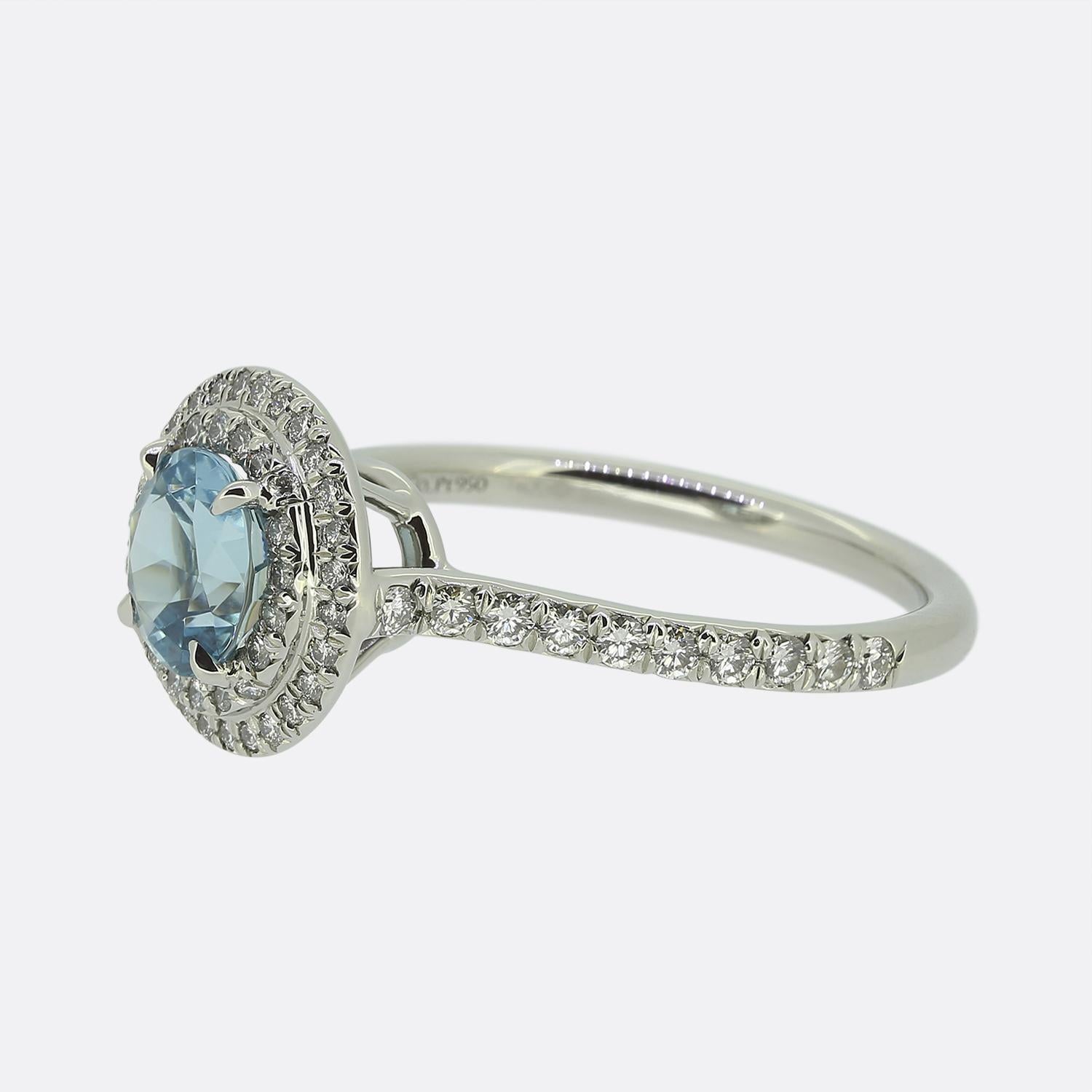 Ecco uno squisito anello a doppia aureola di Tiffany & Co., gioielliere di fama mondiale. Realizzato in platino, questo affascinante pezzo presenta al centro una splendida acquamarina rotonda sfaccettata, che irradia una splendida tonalità di