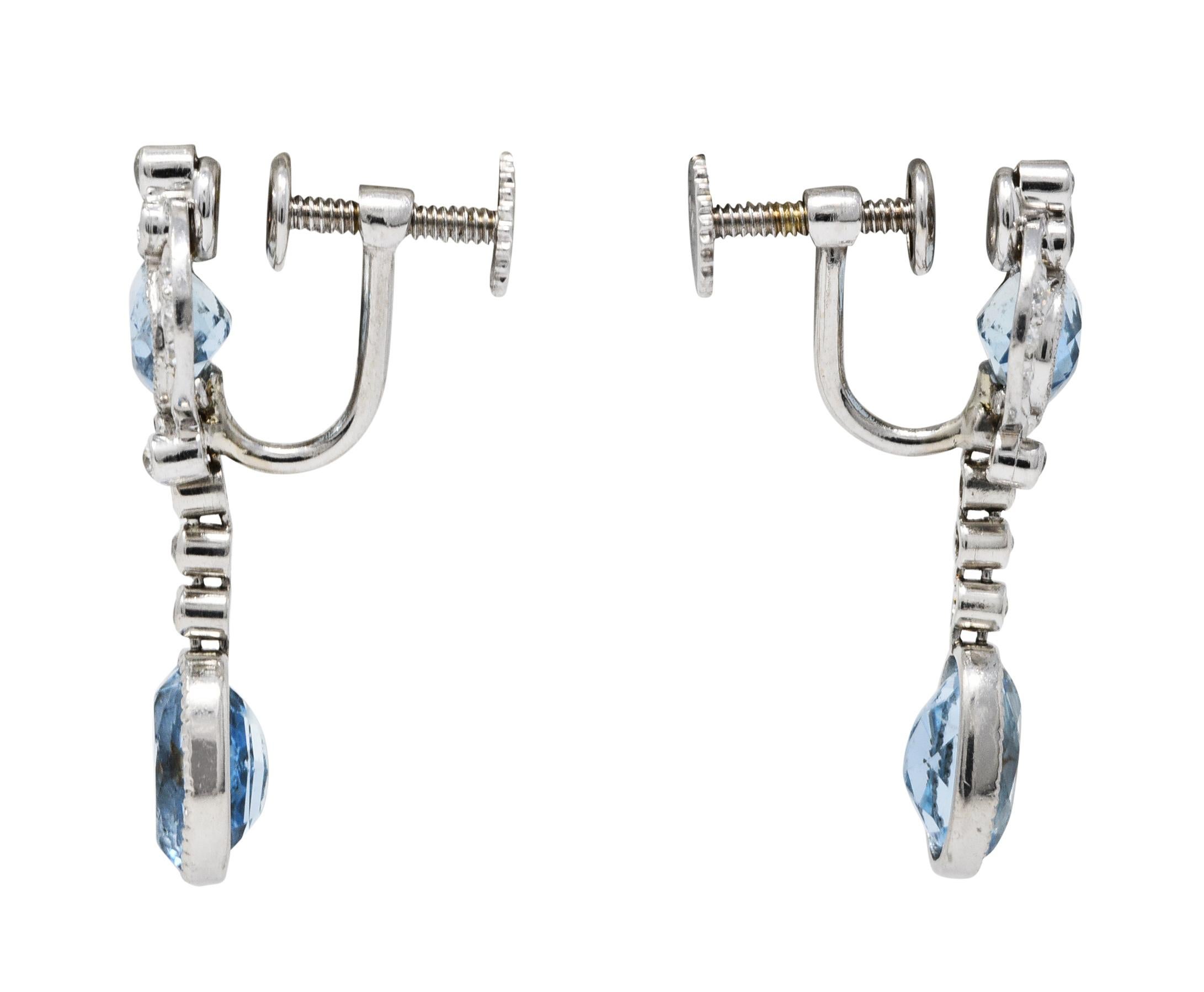Screwback earrings are designed with an ornately scrolling surmount suspending an articulated drop

Featuring oval cut aquamarines weighing in total approximately 5.00 carats

Bezel set, well matched, medium light greenish blue in color

Accented