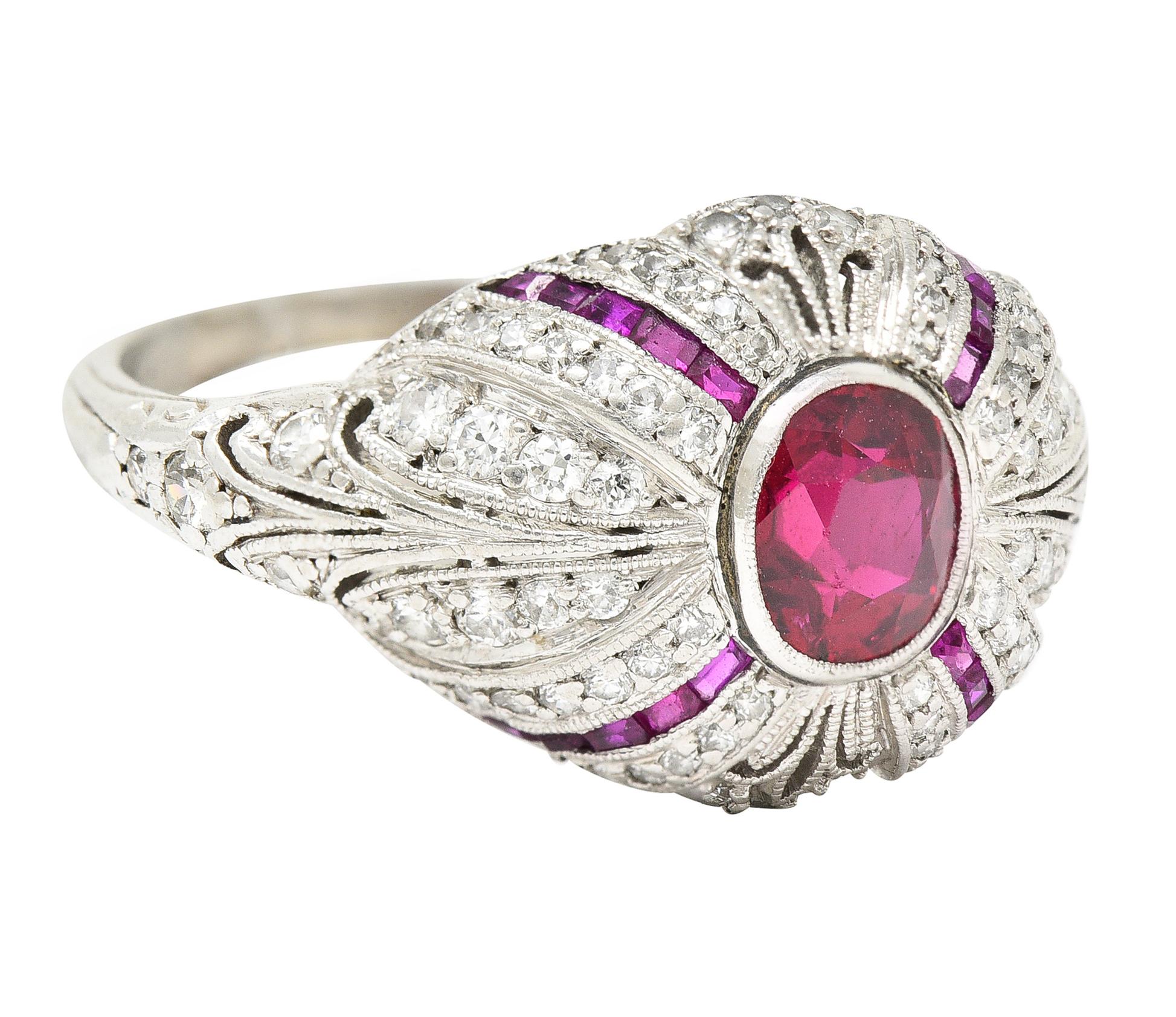 Bombé band ring is pierced with a scroll motif accented by milgrain edges. Centering an oval cut ruby weighing approximately 1.00 carat. Transparent with vivid red color and no indications of heat. Bezel set low in mounting with four channels of