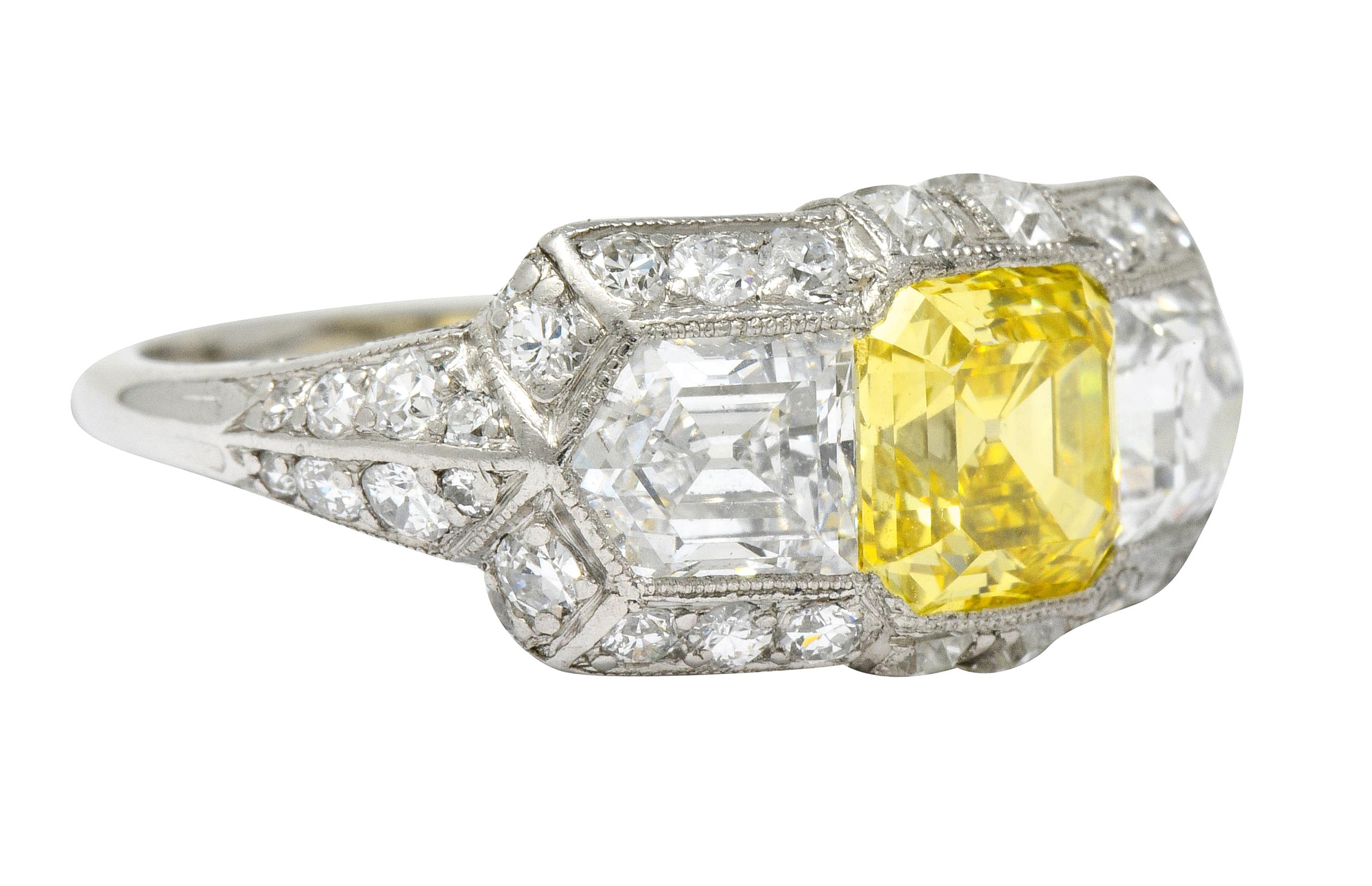 Rectangular mount centers an asscher cut fancy colored diamond weighing 1.43 carats; VS1 clarity and fancy vivid yellow with natural and even color throughout

Flanked by two bullet cut diamonds weighing in total approximately 2.30 carats; D color