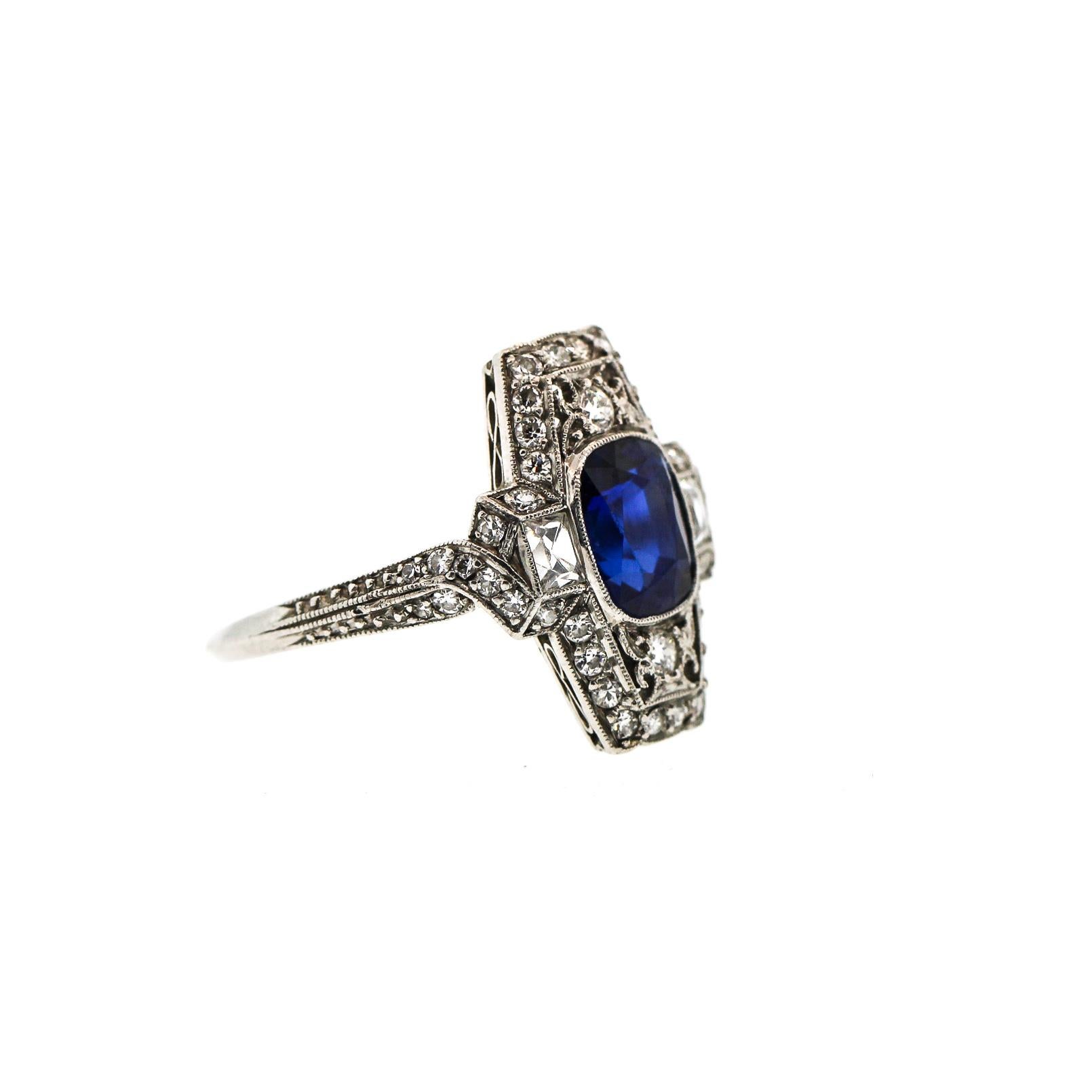 A rare and pristine Art Deco cushion sapphire platinum diamond ring by Tiffany & Co. circa 1925. This ring features a blue cushion shaped sapphire weighing approximately 1.80 ct. The panel ring is set with two French Cut diamonds on the side and